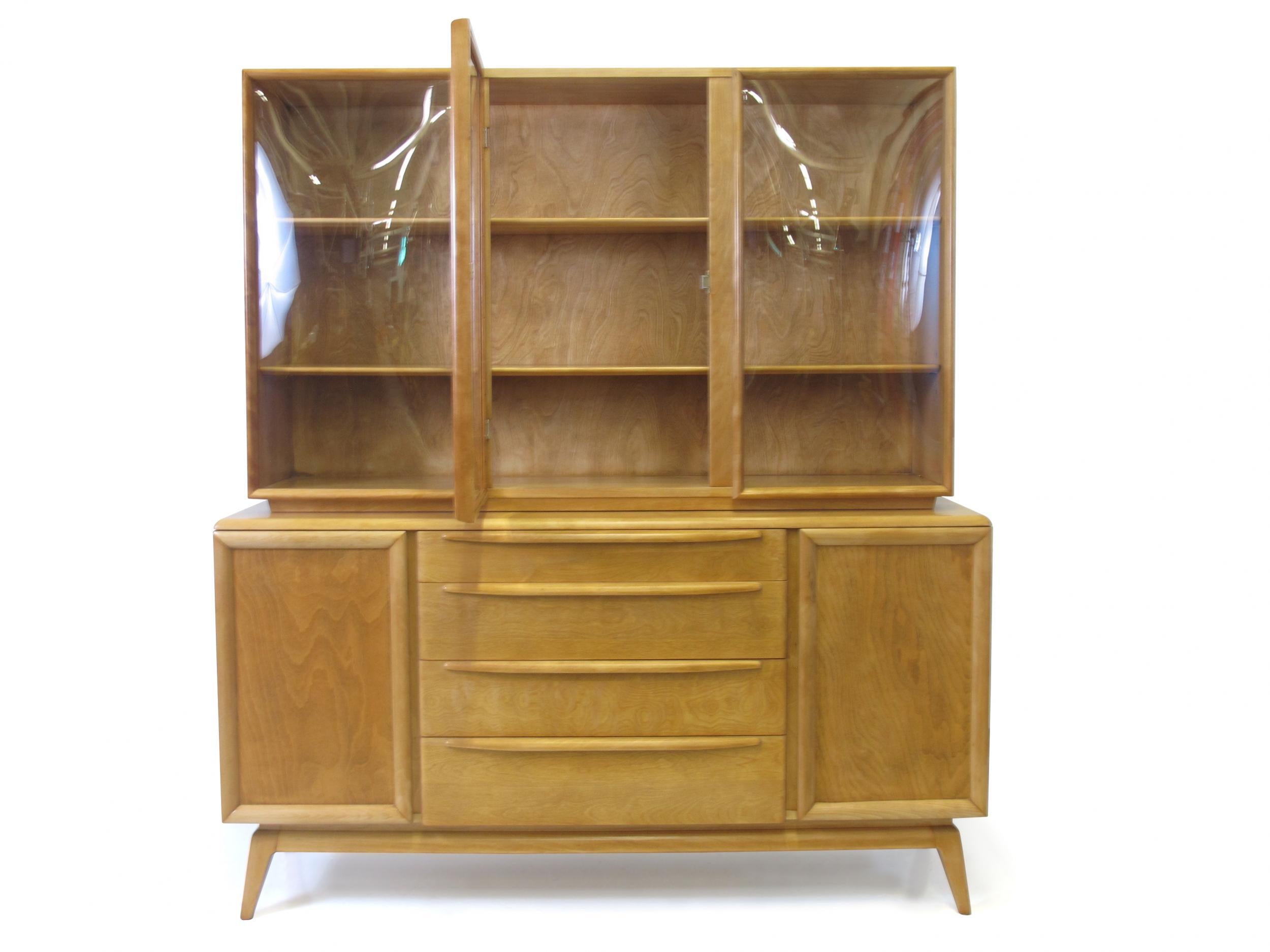 Midcentury sideboard manufactured by Heywood Wakefield. Cabinet crafted of solid birch with pair of doors and series of four drawers in center, with convex glass hutch above with three doors and two adjustable shelves. Very good condition with minor