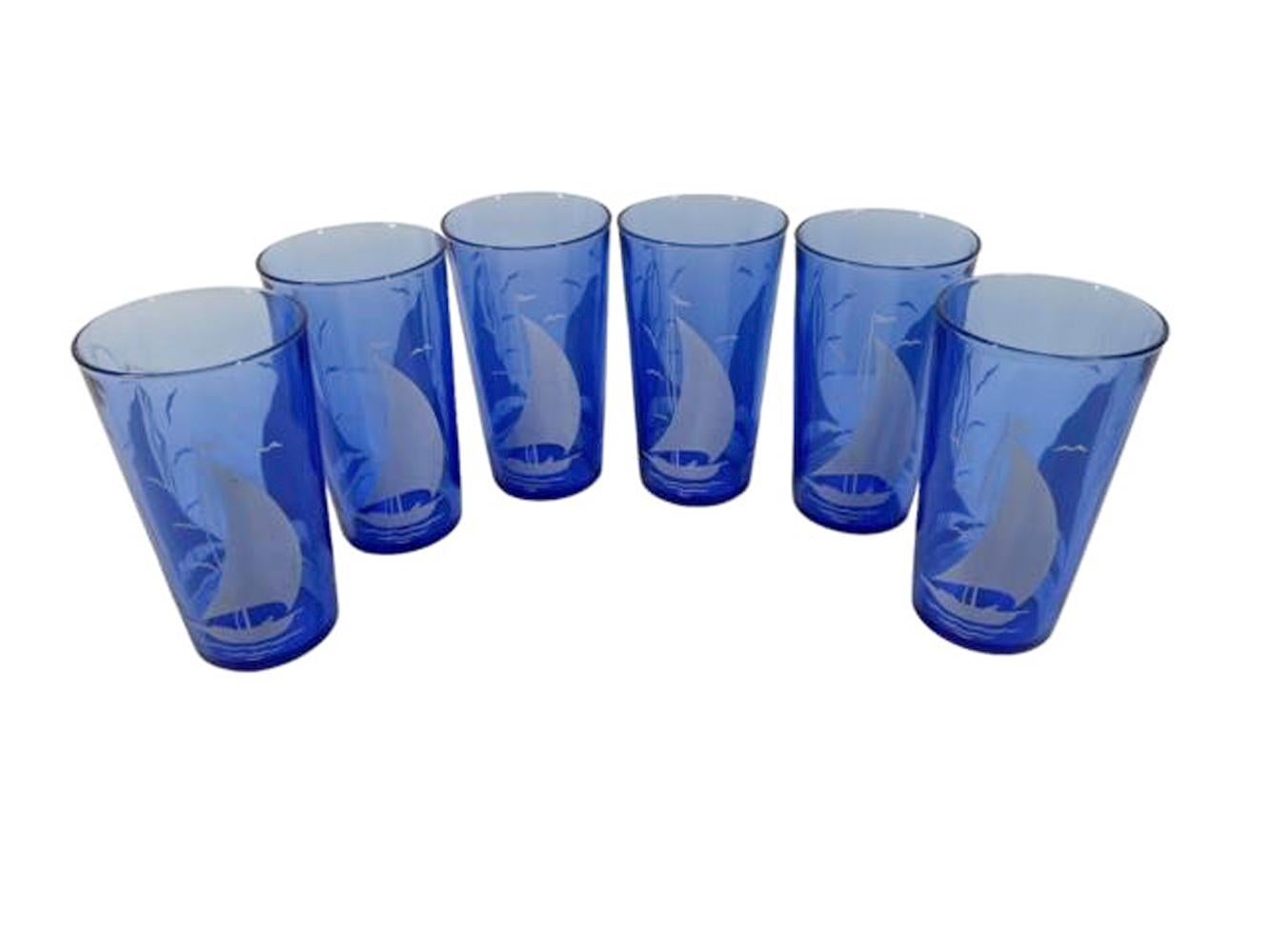Set de sept shakers à cocktail de la série Sportsmans par Hazel-Atlas. Shaker à cocktail bleu cobalt à couvercle chromé et six verres assortis avec voiliers et oiseaux blancs.