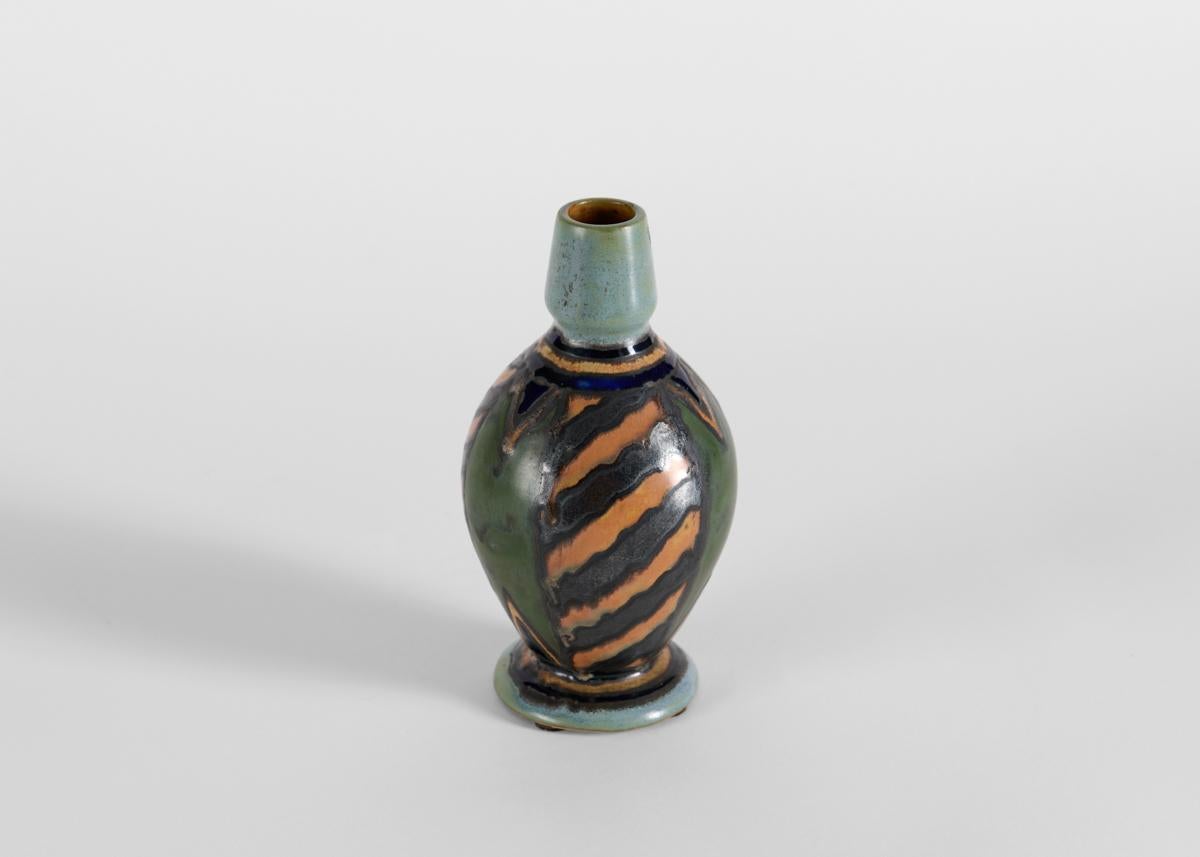 Balluster in shape, the body of this Art Deco vase is glazed in muted, earthy tones with stripes of angled wavy lines that contrast to its pale gray neck and foot. Signed: HB Quimper Odetta

Numbered: 99.1880