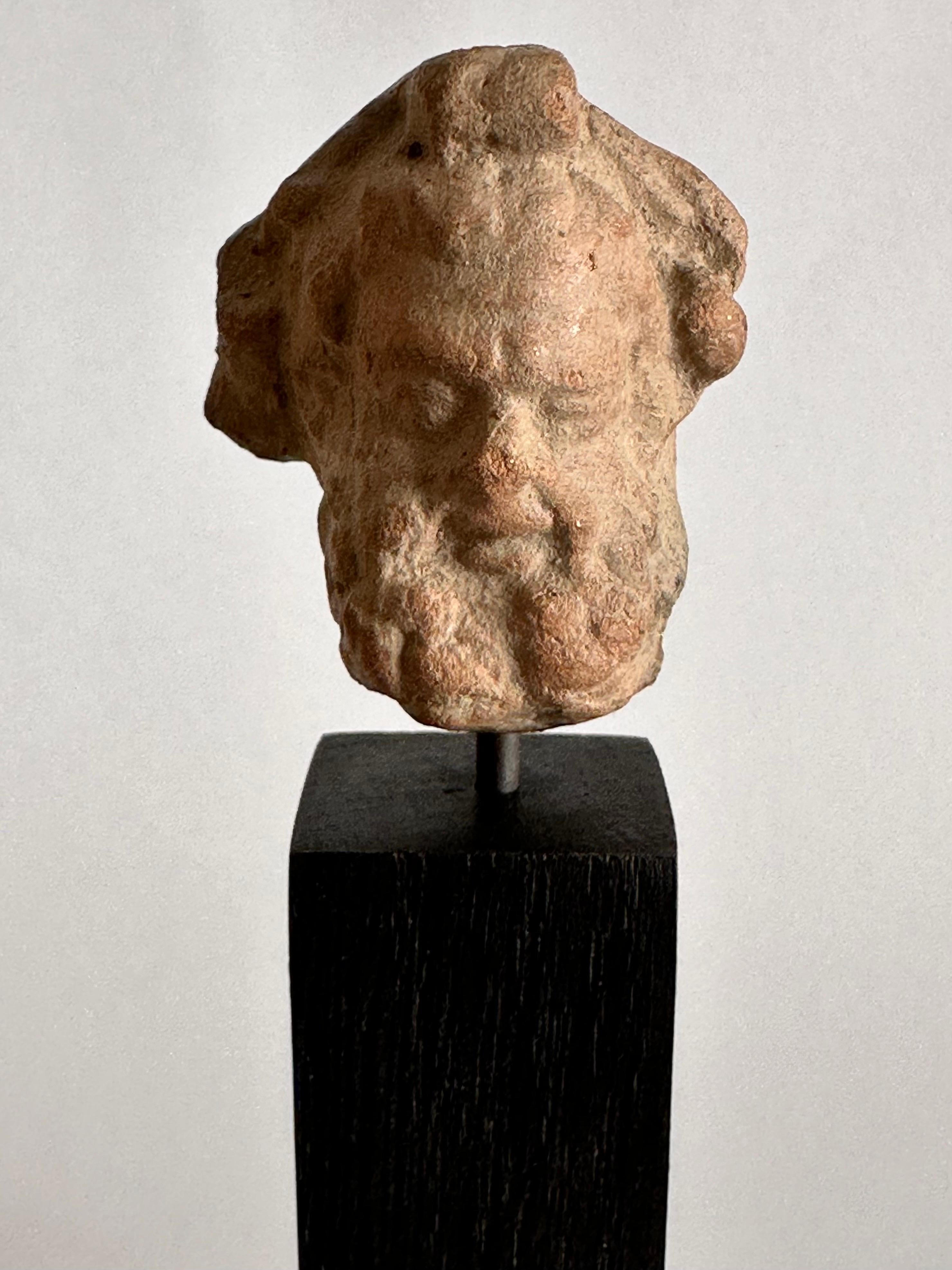 Head of a bearded man.
Terracotta.
Magna Graecia, 4th century before Christ.

Wood and bronze stand.

Height: 3,9 cm.
Overall: 10,7 cm.