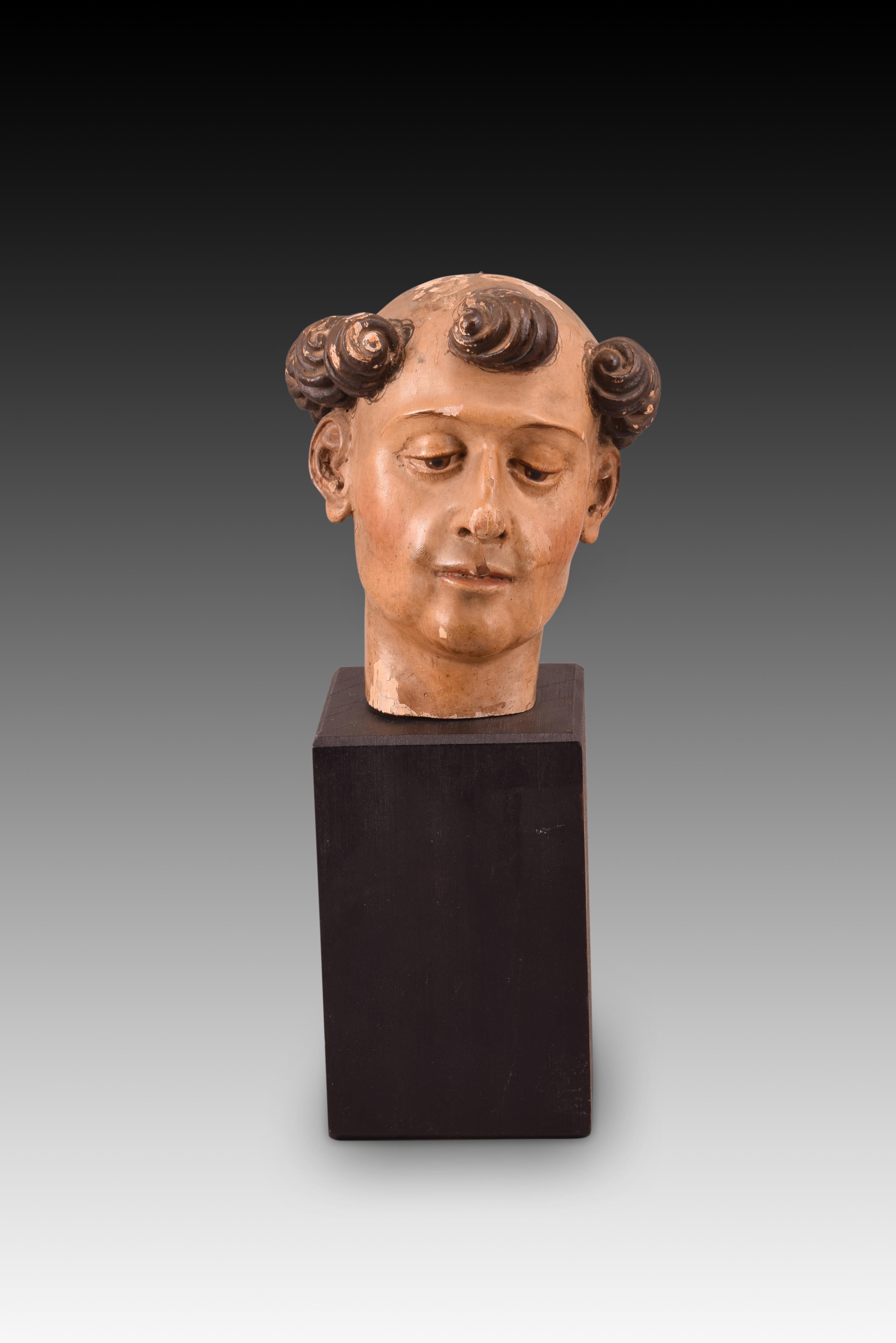 Saint head. Carved and polychrome wood. Spanish school, 17th century. 
Head made of carved and polychrome wood of a young man, with curly and tonsured dark hair, who keeps his gaze lowered. It does not have hairpieces, but follows the usual lines
