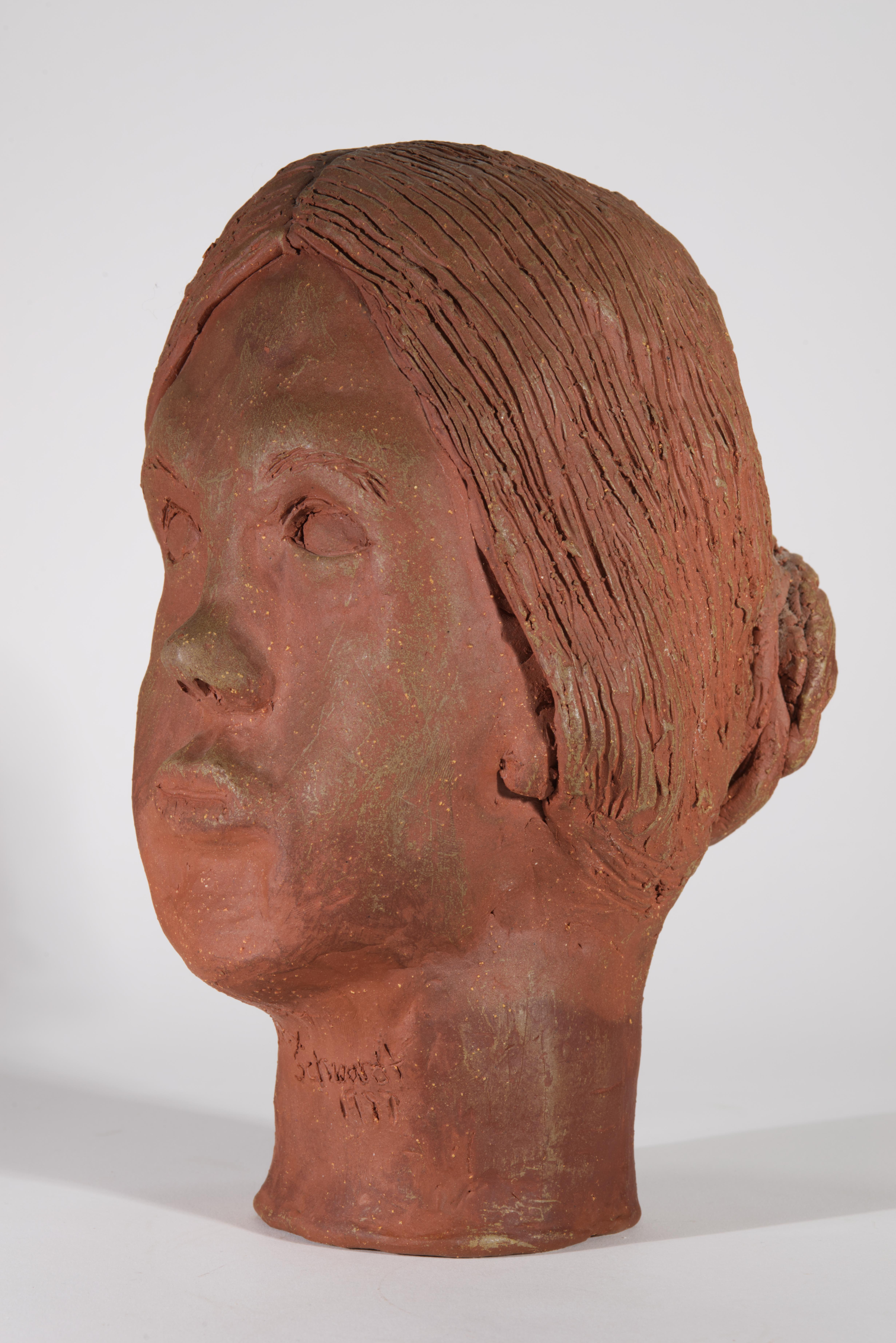  Vintage Modernist ceramic sculpture features a head of young woman, made from raw terracotta and sculpted using the hands and small tools. The model's hair is arranged in low bun on the back of her head; she is looking straight forward with calm,