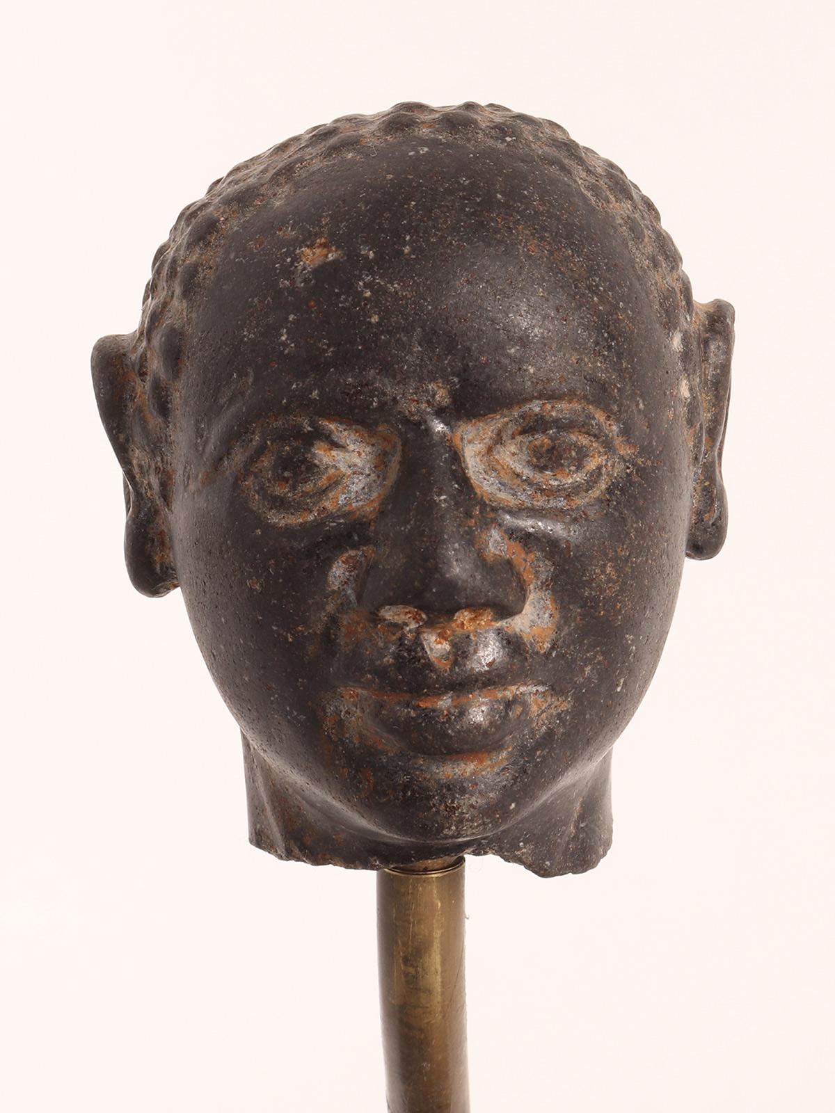 Sculpture depicting a man head made out of black granite, mounted on a square iron base with a brass support. Russia early XVIII century.