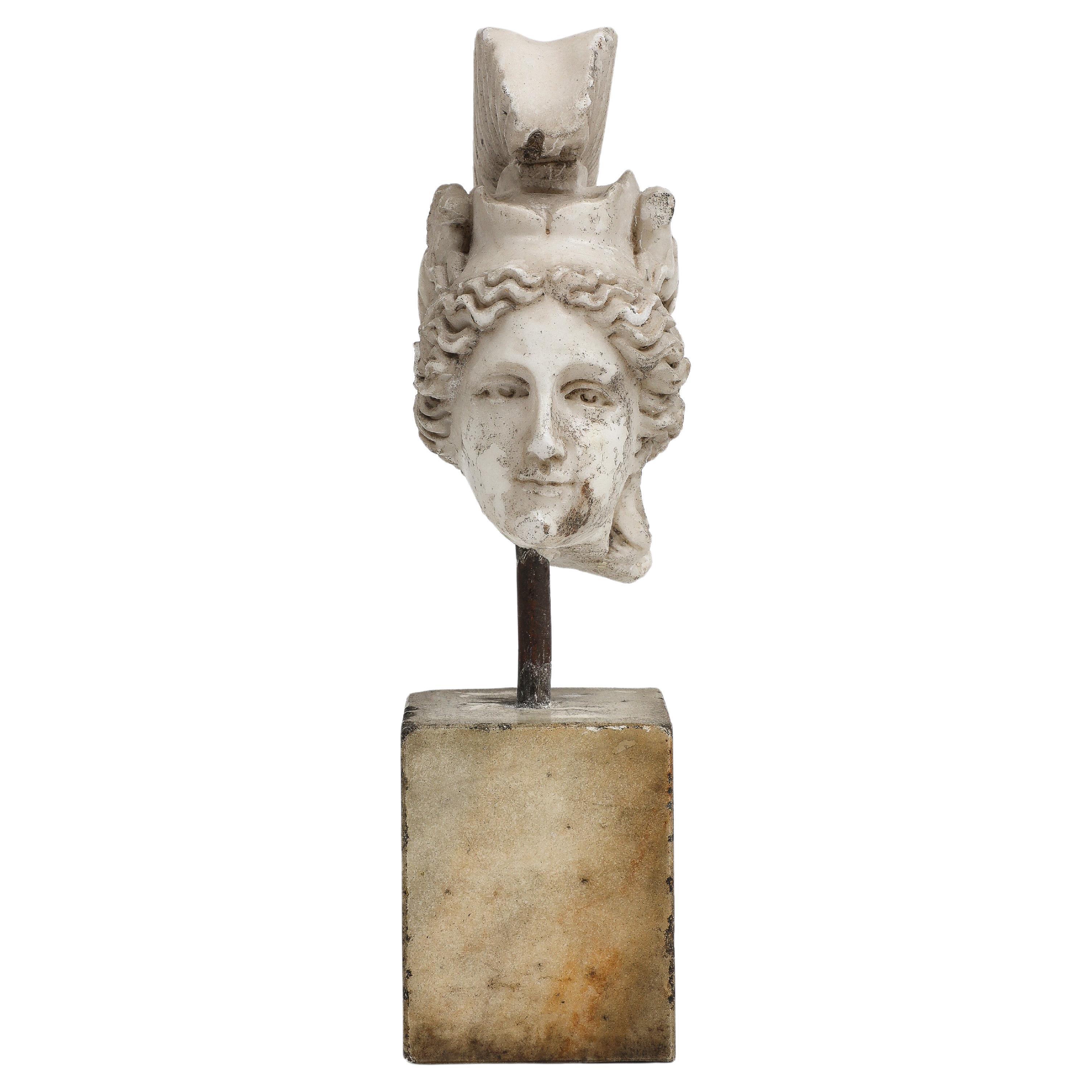 Petite sculpture of the head of Minerva carved in white marble, on a parallelepiped base, 19th Century Greek. 

Minerva is the Roman goddess of poetry, medicine, commerce, weaving, the crafts, and wisdom. She is depicted here with a helmet adorned