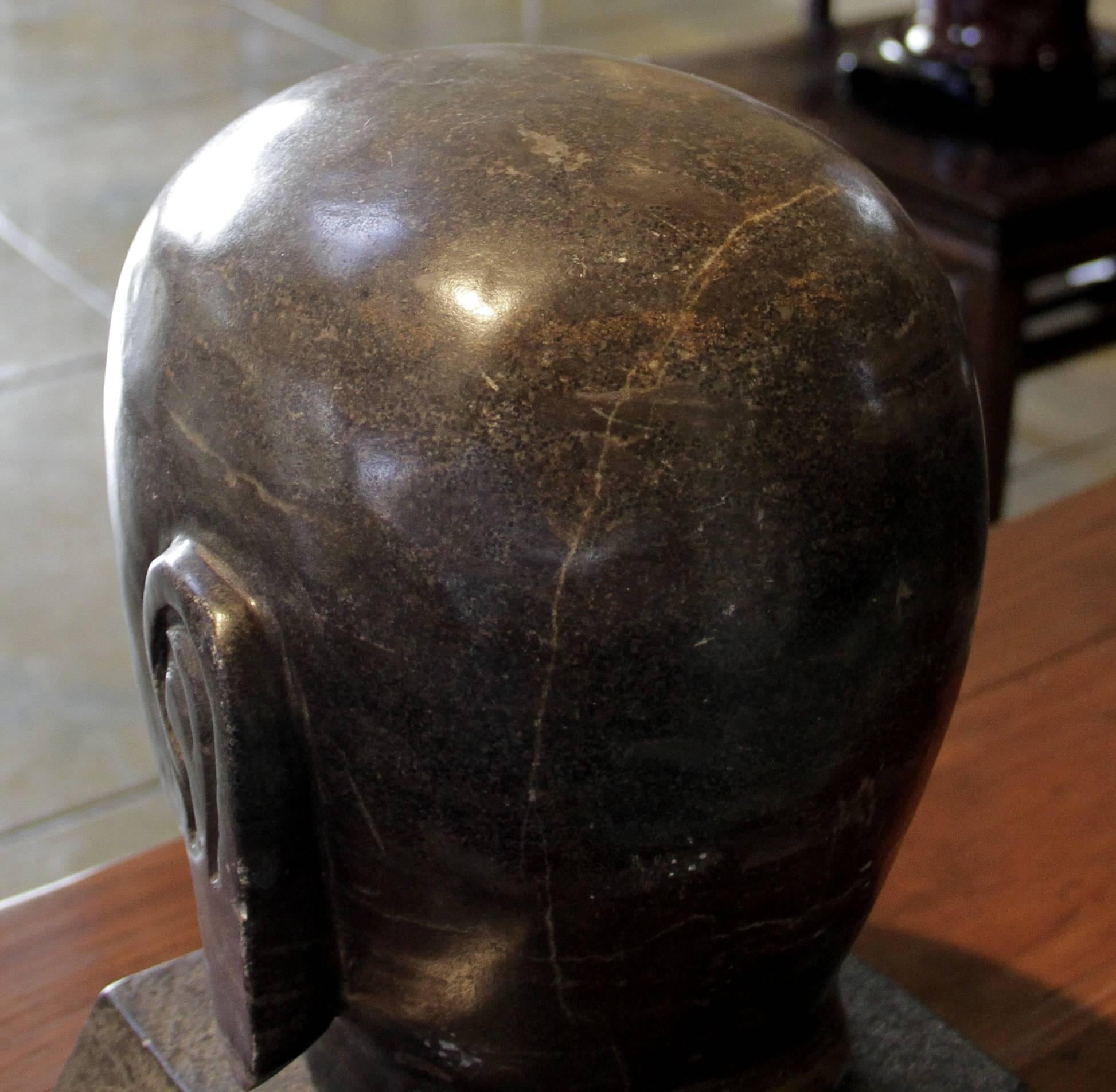 This carved granite sculpture is that of a head of a monk. It was hand-carved in China in the 19th century, circa 1880. It sits on a custom stone stand.