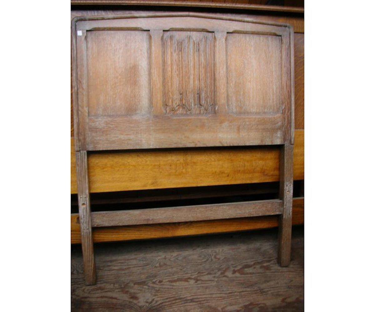 Heals. An Arts & Crafts limed oak single bed with arched tops and linenfold details to the centre panels. 
We do have the iron side rails to put the base on, it will require a new base or slats to hold a mattress.
Measures: Headboard Height 43 3/4