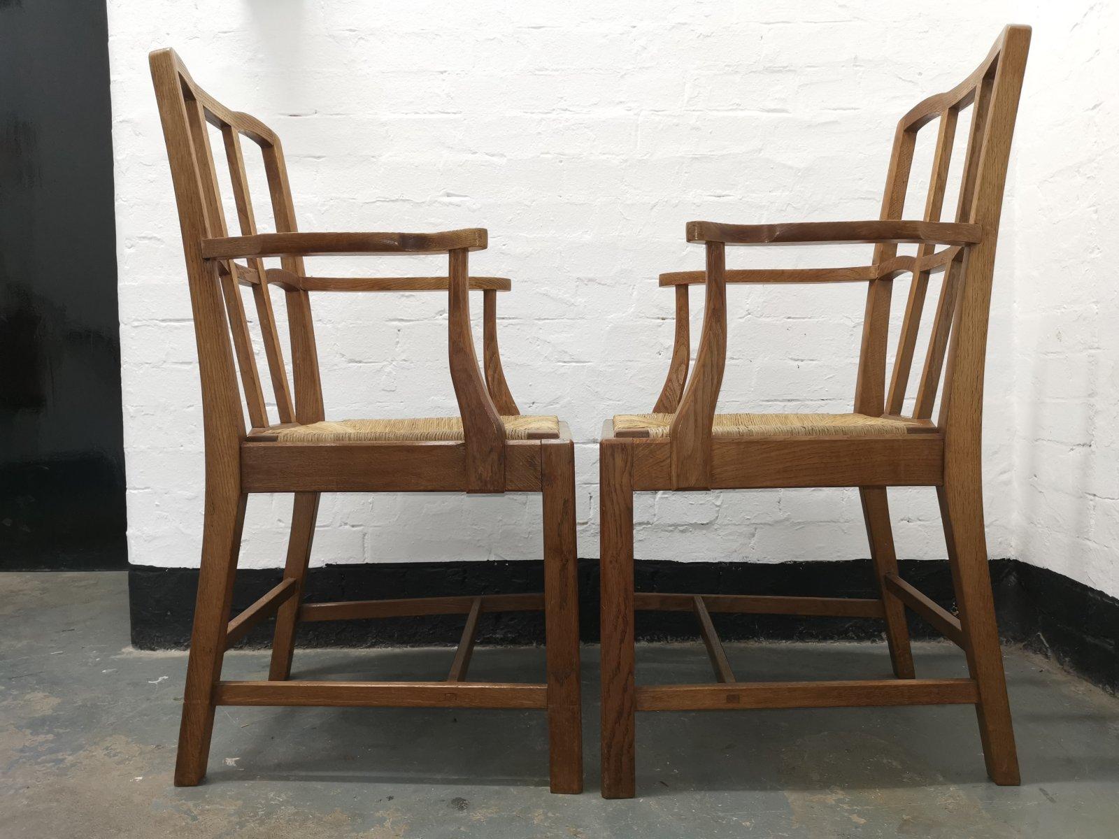 A pair of English Cotswold School Arts & Crafts oak lattice back armchairs with subtle arches to the lattice backs, shaped arms, and pegged construction retaining the original rush seats in great condition.
Good quality sculptural craftsmanship.