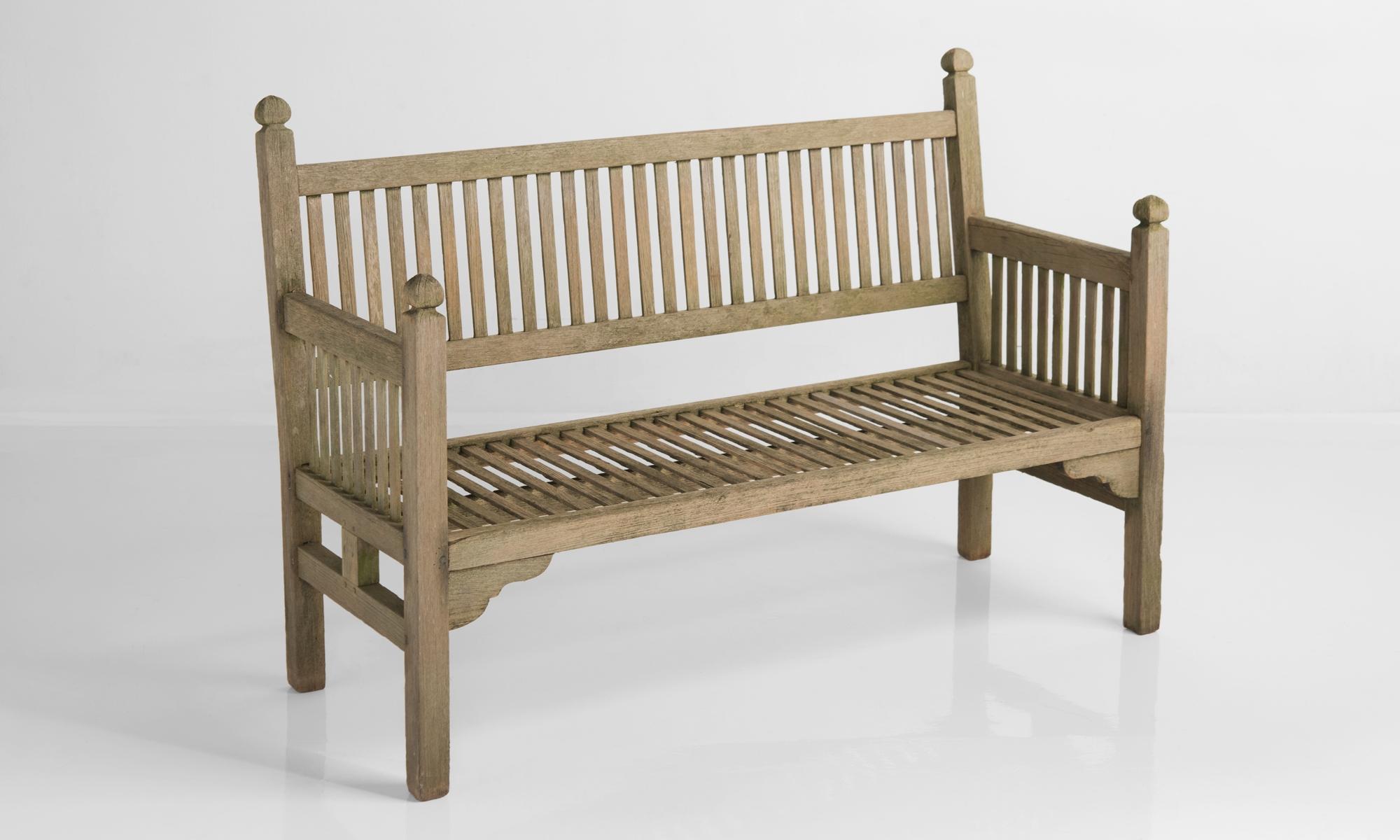 Heals Edwardian garden bench, England, circa 1910.

In patinated teak with finial uprights, made by Heals of London.
