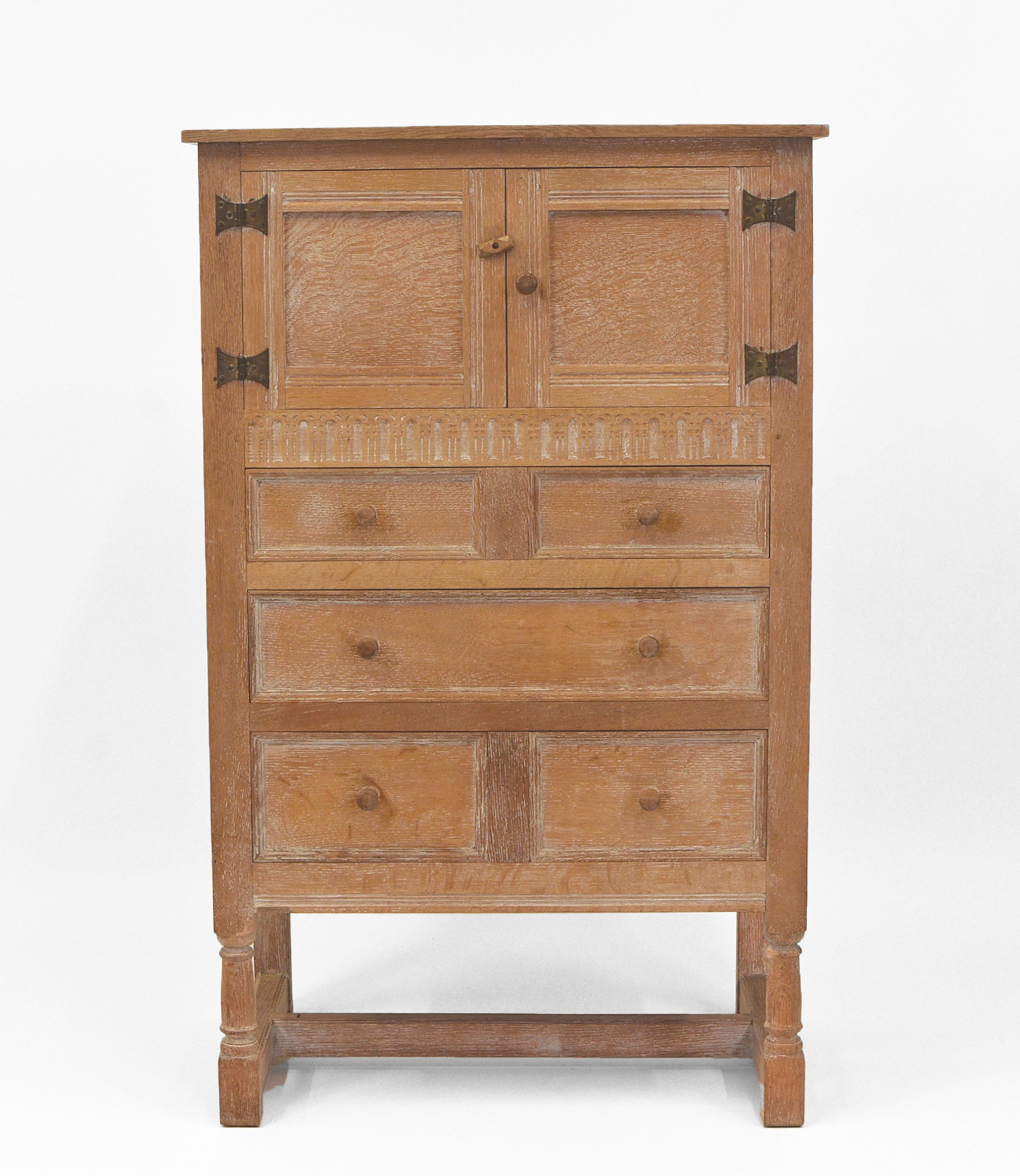 Limed oak tallboy/cabinet of good proportions by Heal & Son. Circa late 1930's.

Superbly made, with each join having dowel construction. Single band carved decoration and forged iron exposed cabinet door hinges. Made in solid oak with inner