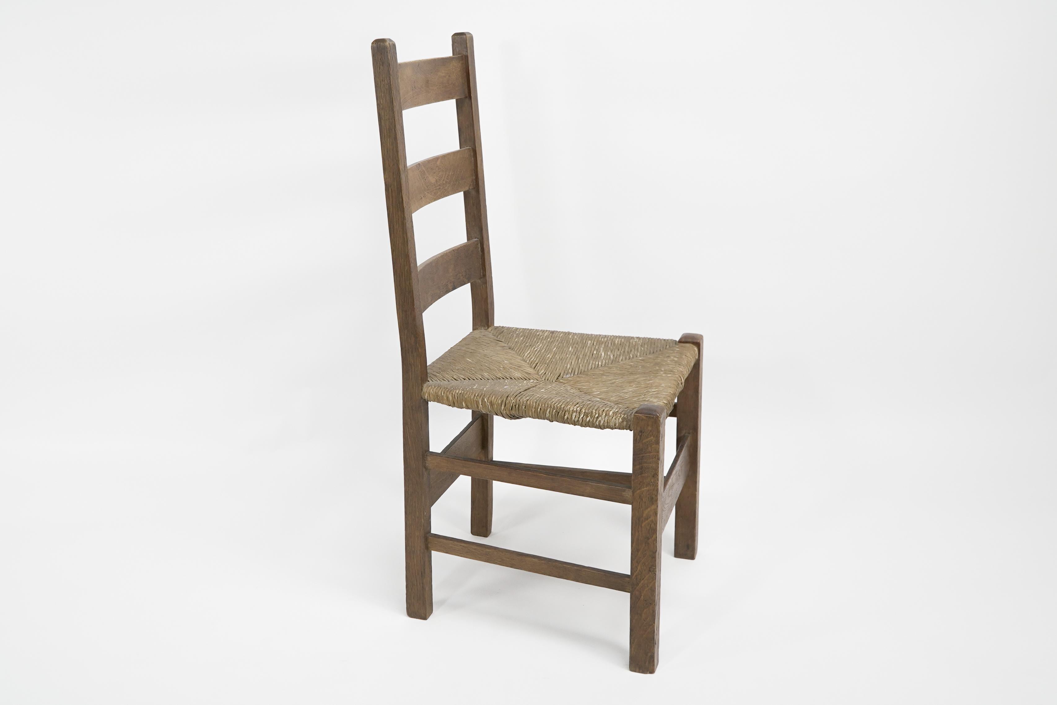 Heals. London. An Arts and Crafts ladderback with original rush seat and plank stretchers to the front and back legs.