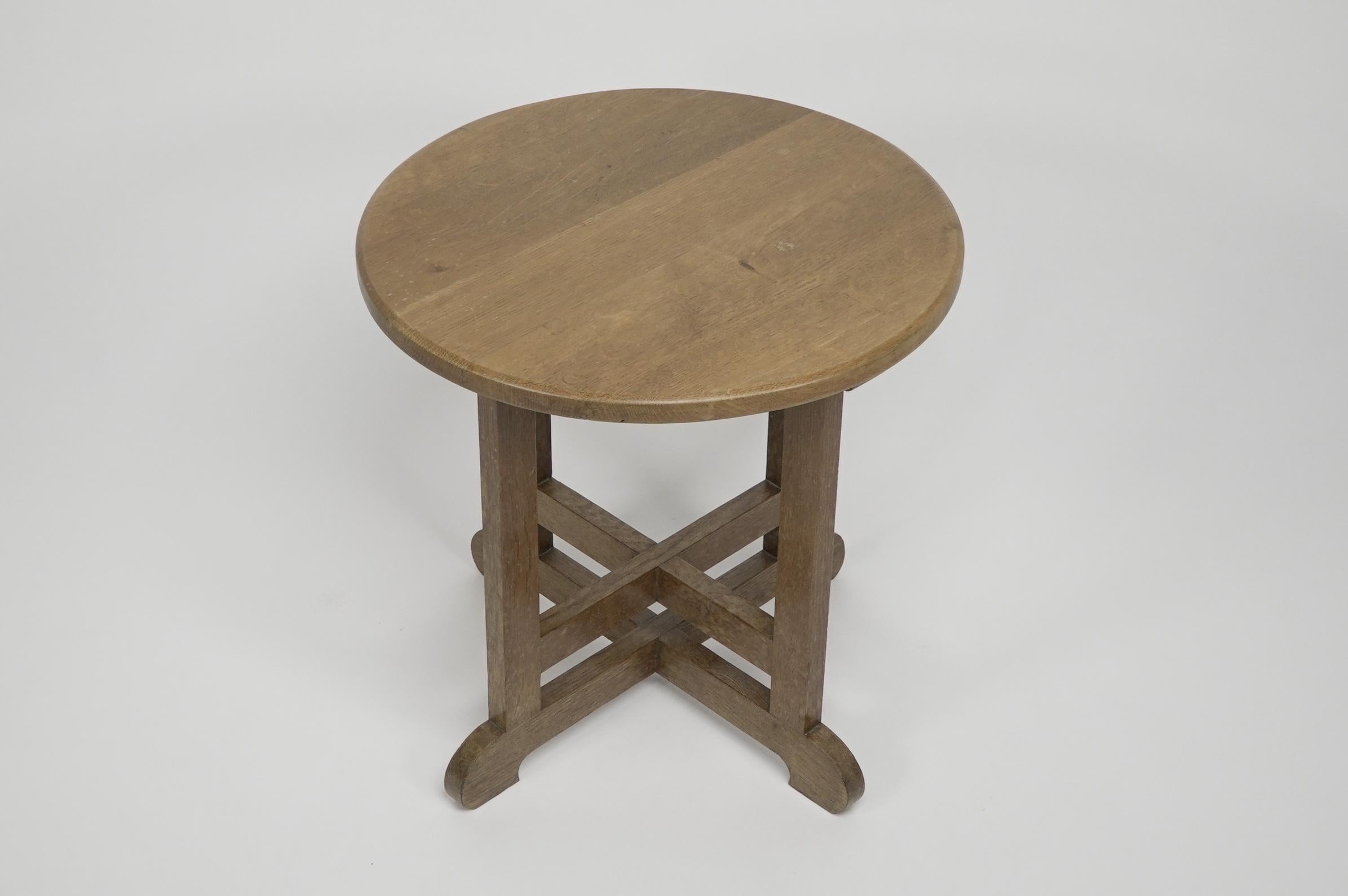 Heals, in the style of. An oak Arts and Crafts circular oak side or occasional table with double cross stretchers making a stronger design detail, raised on little curved feet.