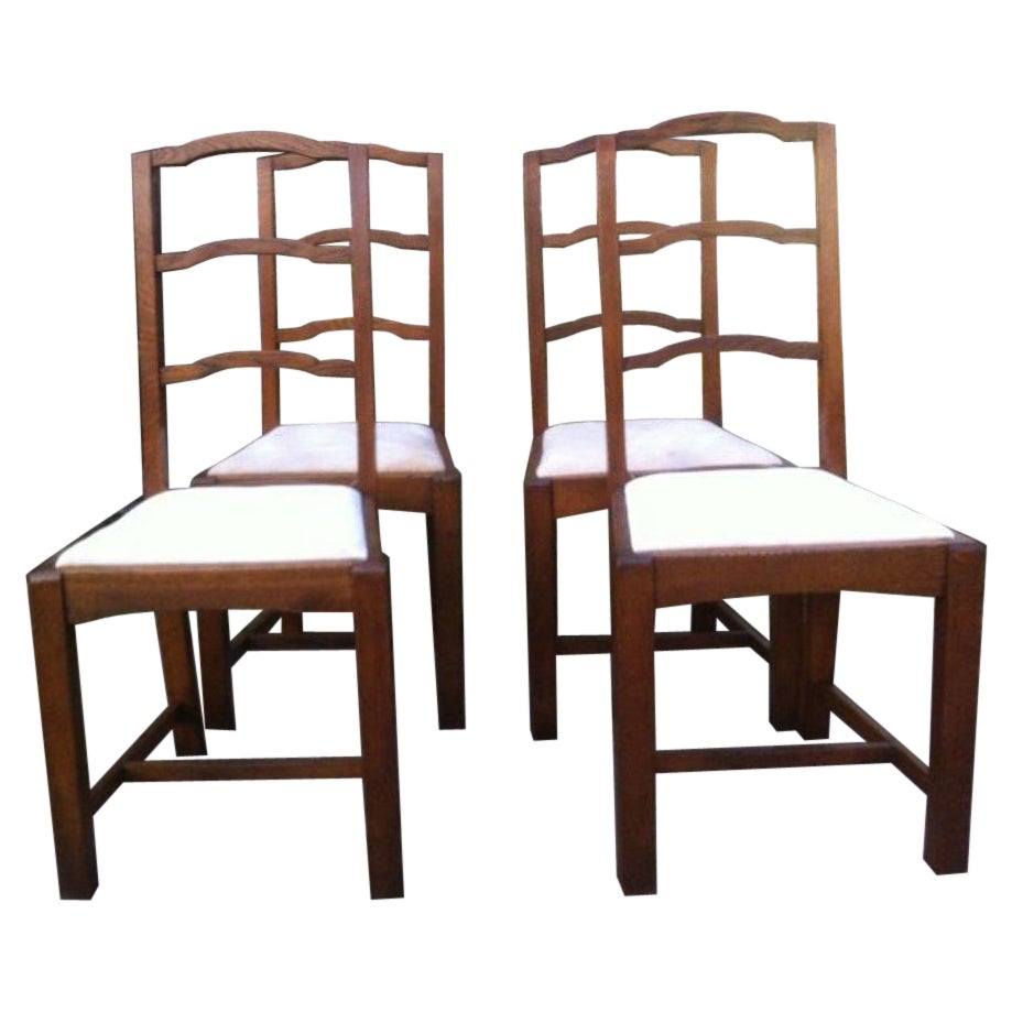 Heals, ensemble de quatre chaises de salle à manger anglaises Arts & Crafts en chêne arqué avec dossier en échelle