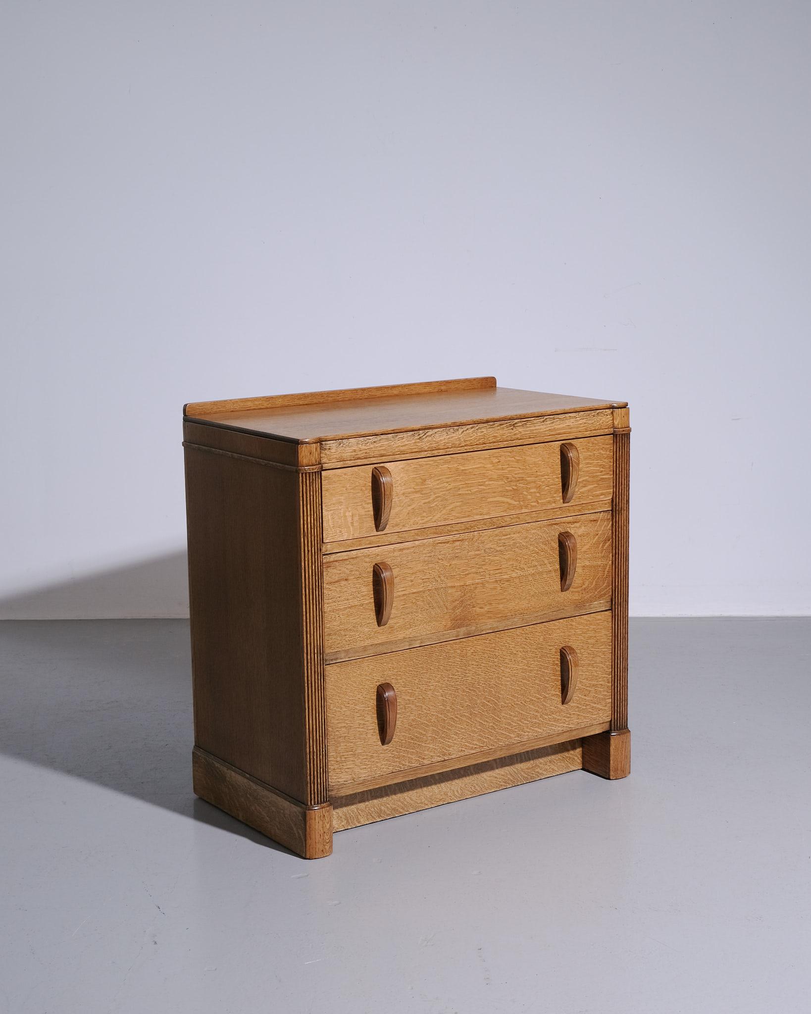 A beautifully proportioned ‘Odeon’ chest of drawers by Heals & Sons, crafted in solid English oak, c.1930s. This piece features the clean lines, subtle detailing, and honest construction that define Heals’ early 20th-century aesthetic. The drawers