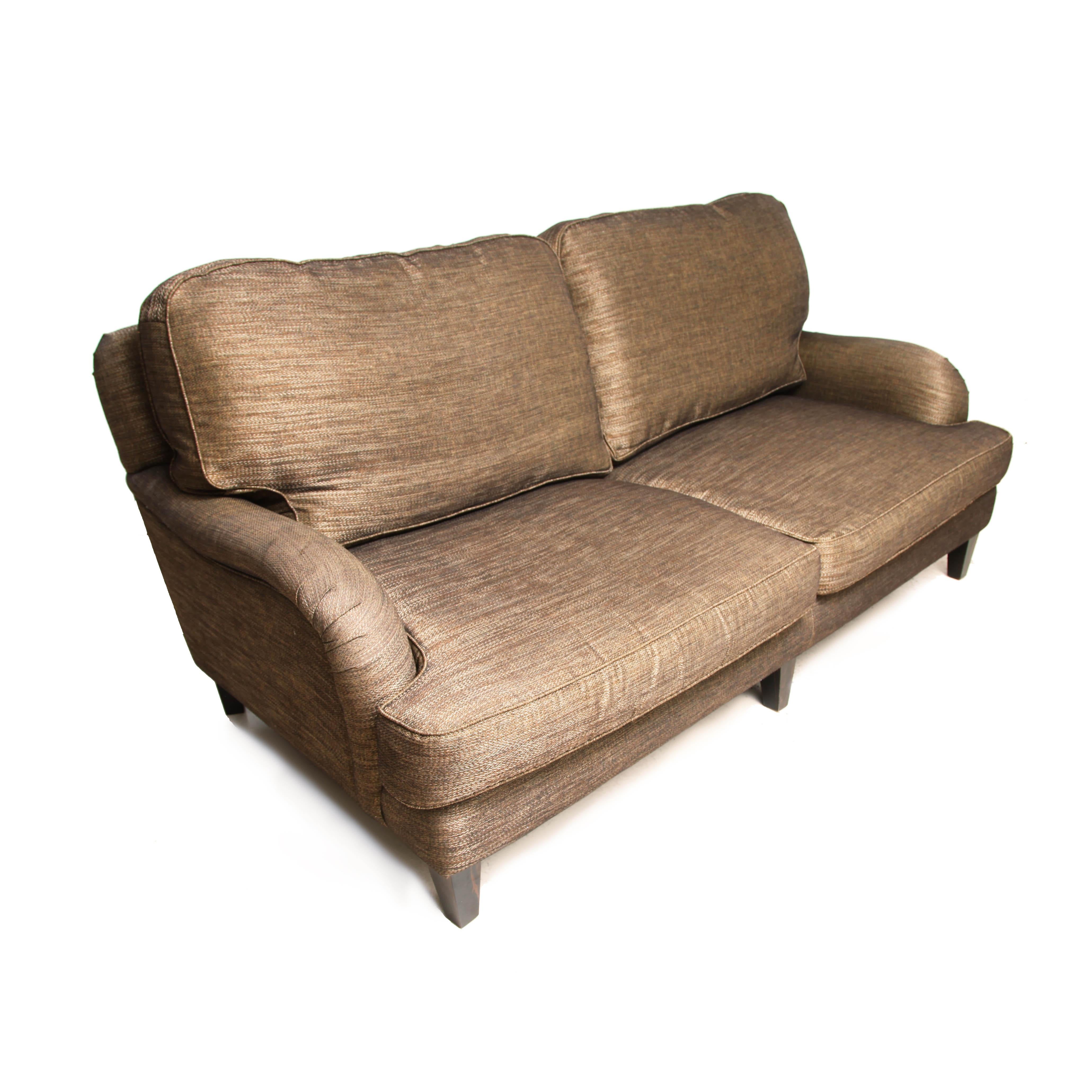 Classic Howard three-seat sofa in brass-gold-browny/bronzed effect upholstery fabric by Tamarisk and goose feathered filled cushions. Overall good condition and comfortable but the left arm side is water stained. Maybe it would benefit new