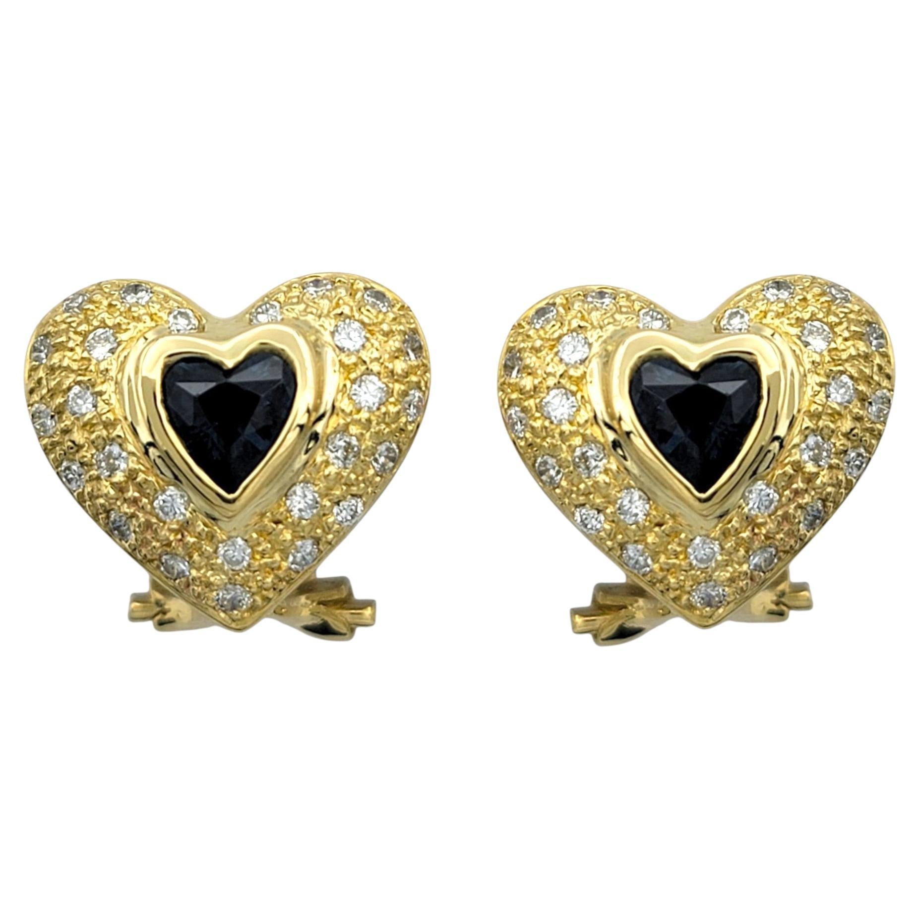 Questi incantevoli orecchini sono caratterizzati da zaffiri blu scuro a forma di cuore che irradiano un colore ricco e accattivante. Gli zaffiri sono splendidamente incorniciati da diamanti di taglio rotondo, che aggiungono un brillante alone di