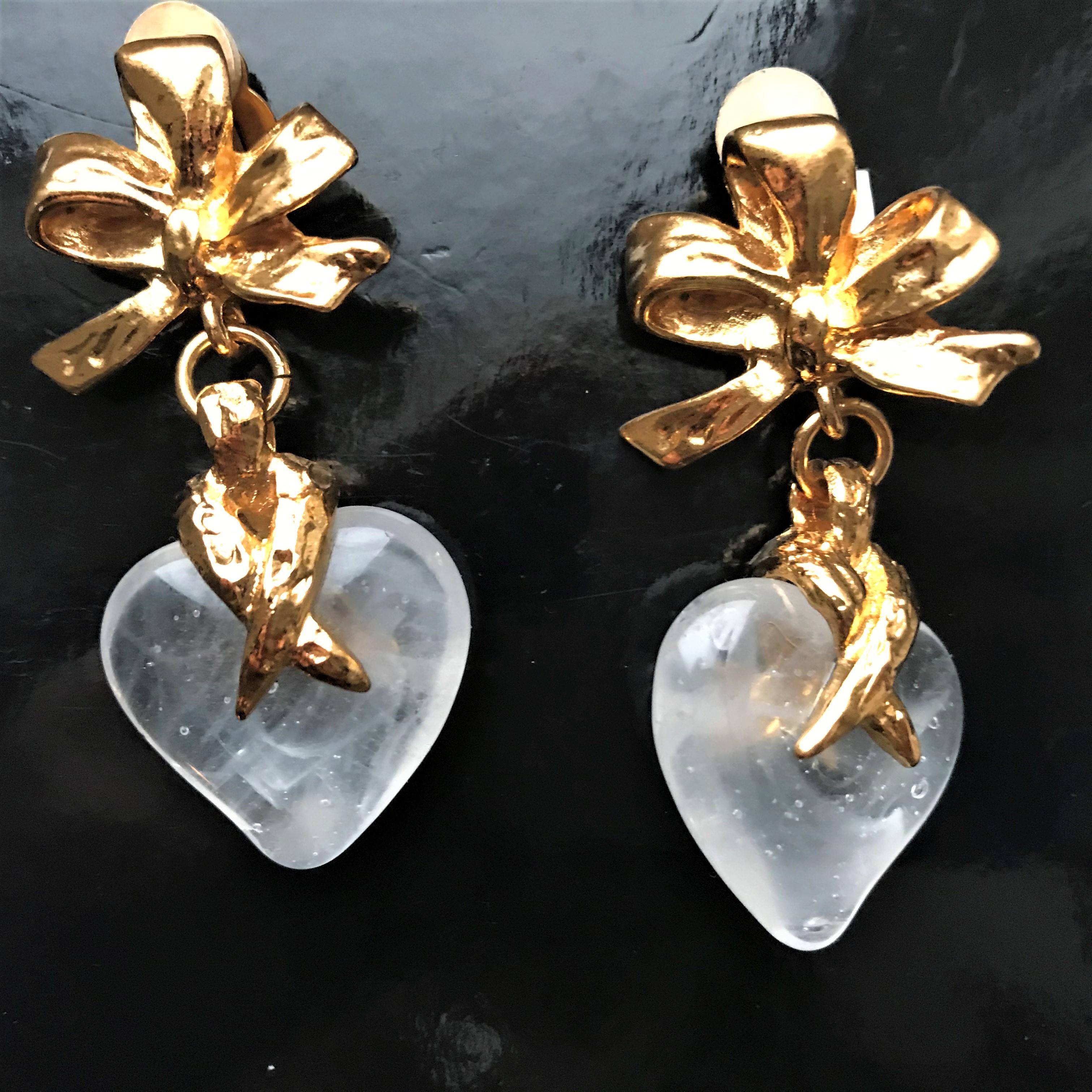 Valentin's day is coming soon !
Very lovely ear clips by Yves St. Laurent on a gold-plated bow hangs a transparent plastic heart. You'd think the heart is made of roc crystal. Inside you can see small bubbles and bullet holes, like the rock