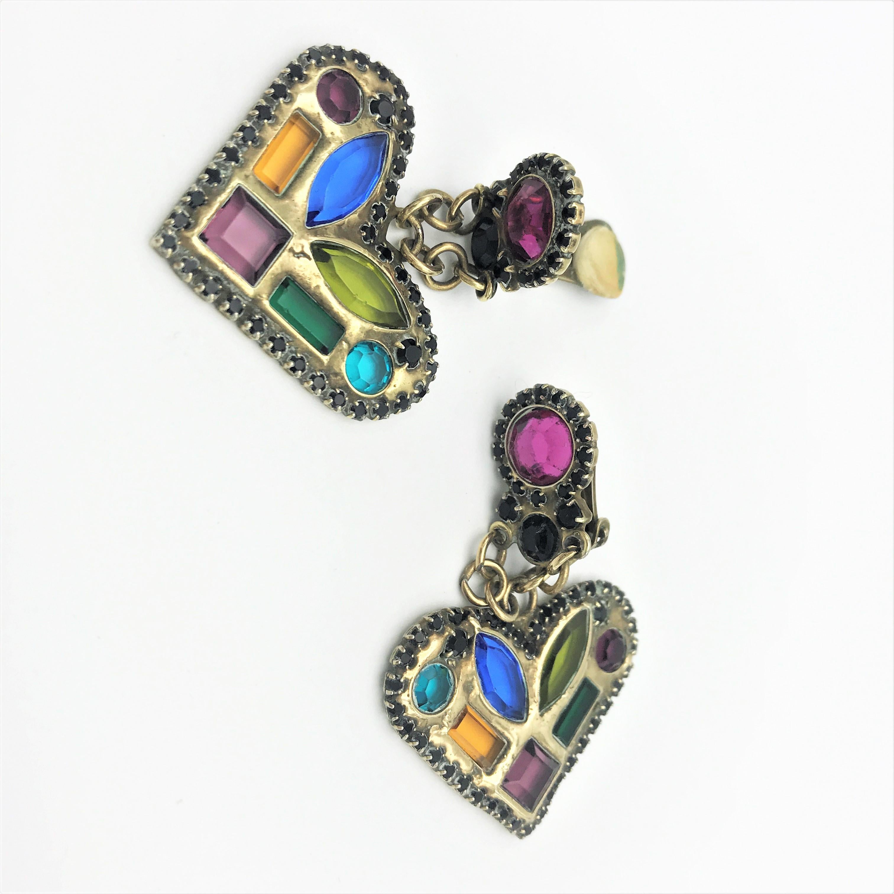 An extraordinary heart with inlaid cut colorful rhinestones. The heart is bordered with individually set small rhinestones and this hangs on a pink colored top, also bordered with the finest rhinestones.
The ear clip is made of brass in the 1980s