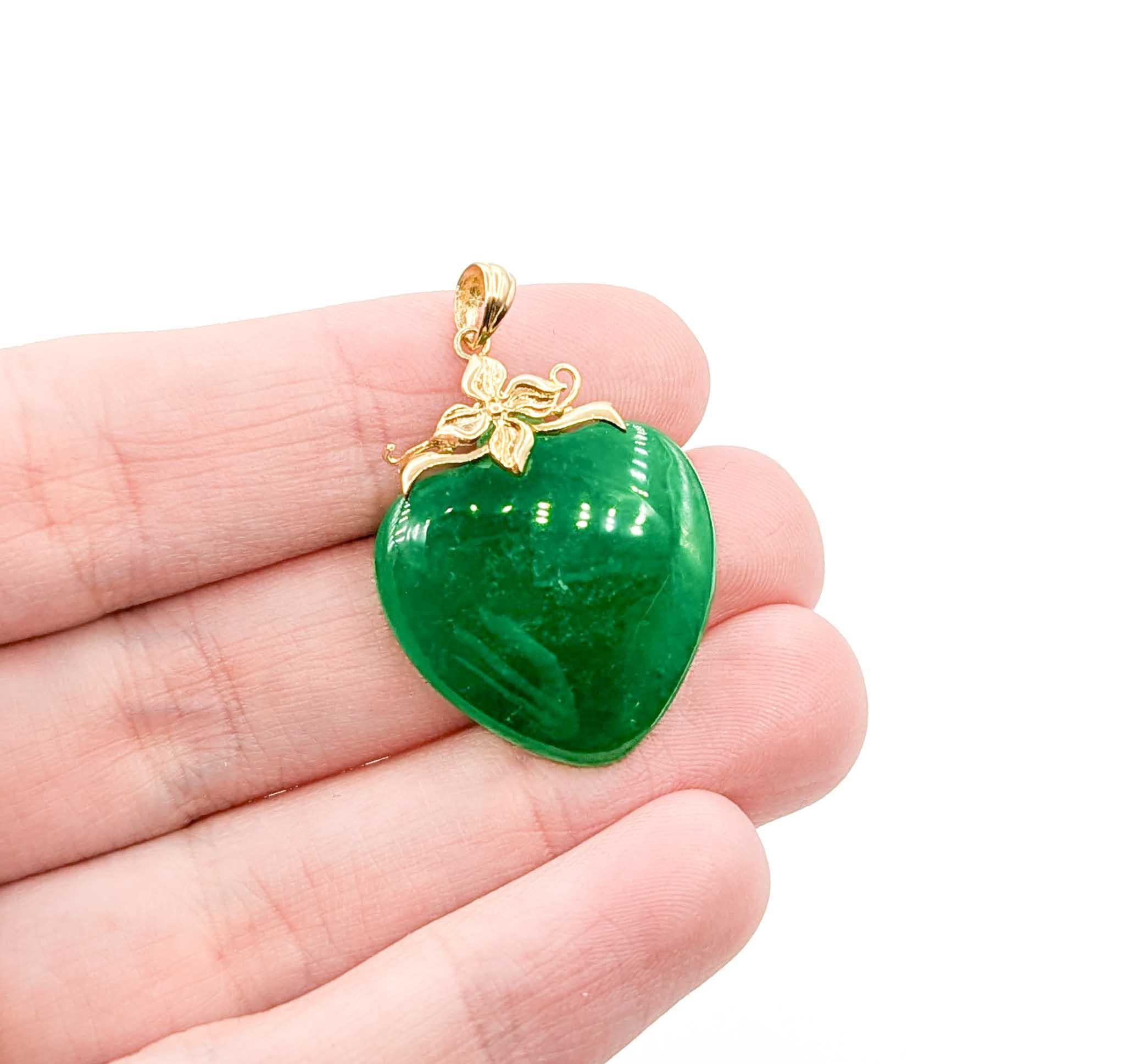 Cet élégant pendentif est réalisé en or jaune 14k et met en valeur un jade en forme de cœur magnifiquement poli mesurant 30 mm sur 20,5 mm. Le riche jade vert est rehaussé d'une délicate boucle florale en or, qui ajoute une touche raffinée au
