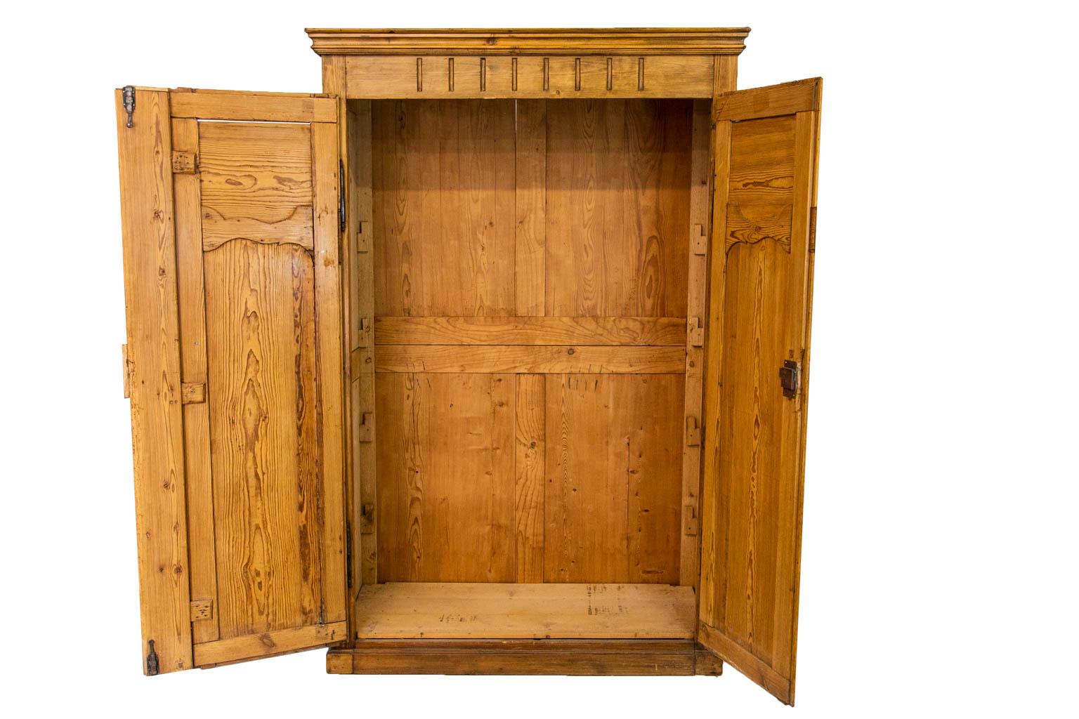 The frieze and center stile of this armoire are fluted. The doors are framed with shaped moldings and have raised panels that are also framed by shaped moldings. There are support structures for four shelves inside. Currently there are no shelves.