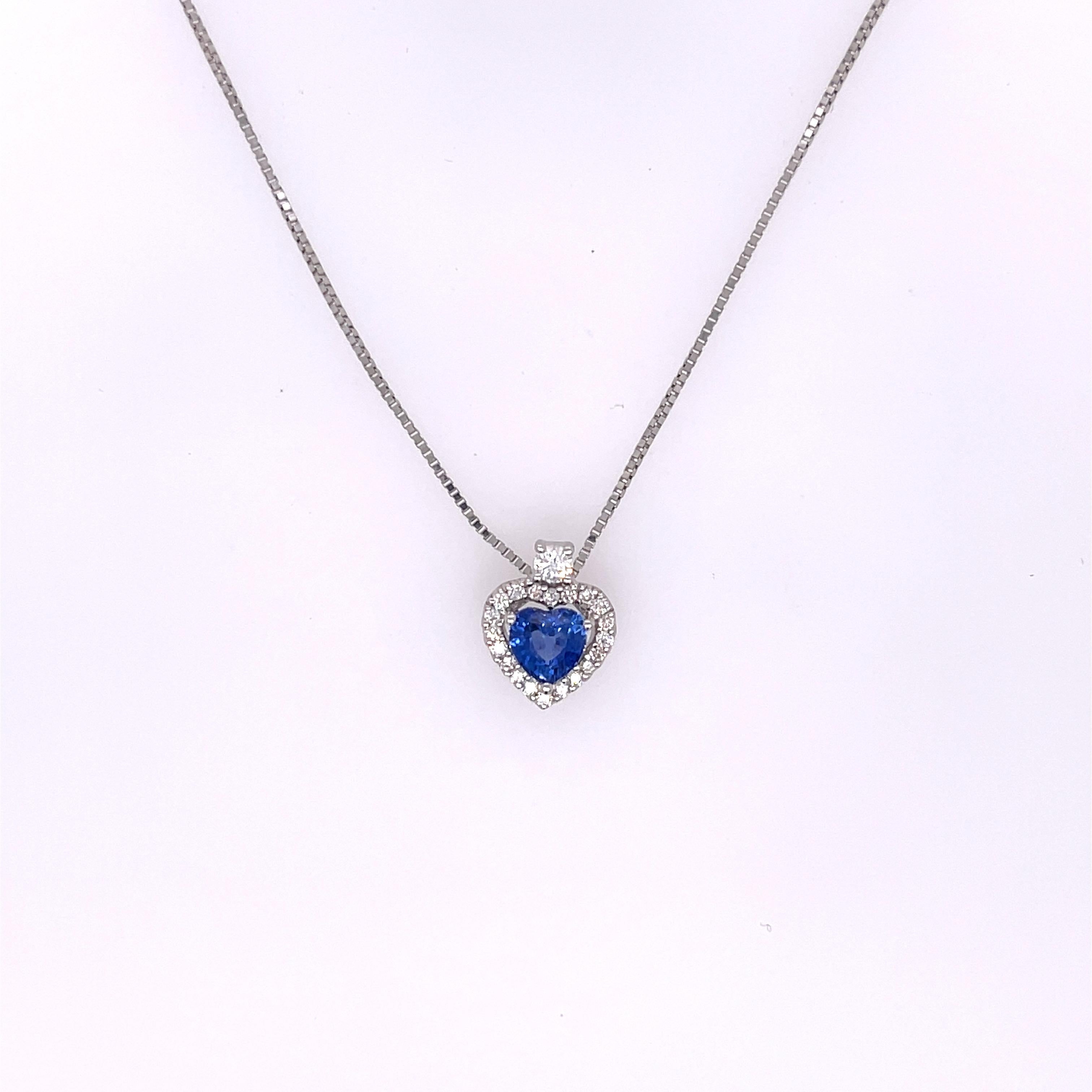Pendant necklace featuring a 0.46ct heart shaped sapphire and a halo of 0.15ctw of brilliant cut round diamond in 14K white gold. The pendant is approximately 10.85mm by 8.70mm.