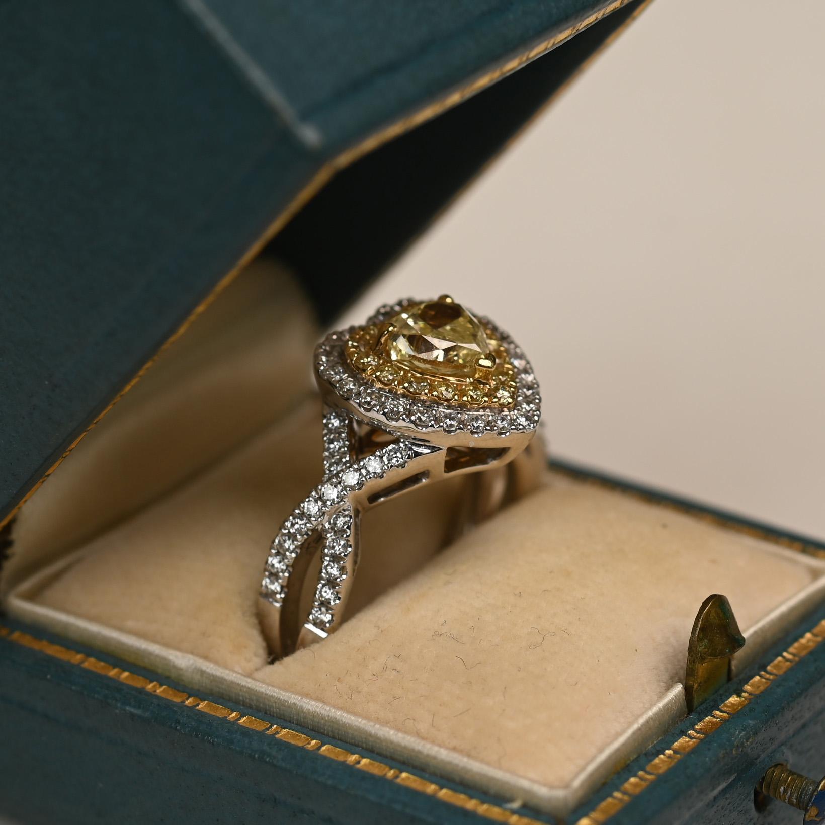 Questo splendido anello presenta al centro un diamante giallo a forma di cuore di circa 0,90 carati, con una gradazione di purezza VS1. La pietra vibrante è incorniciata da una doppia aureola di diamanti gialli e bianchi, che ne esaltano la