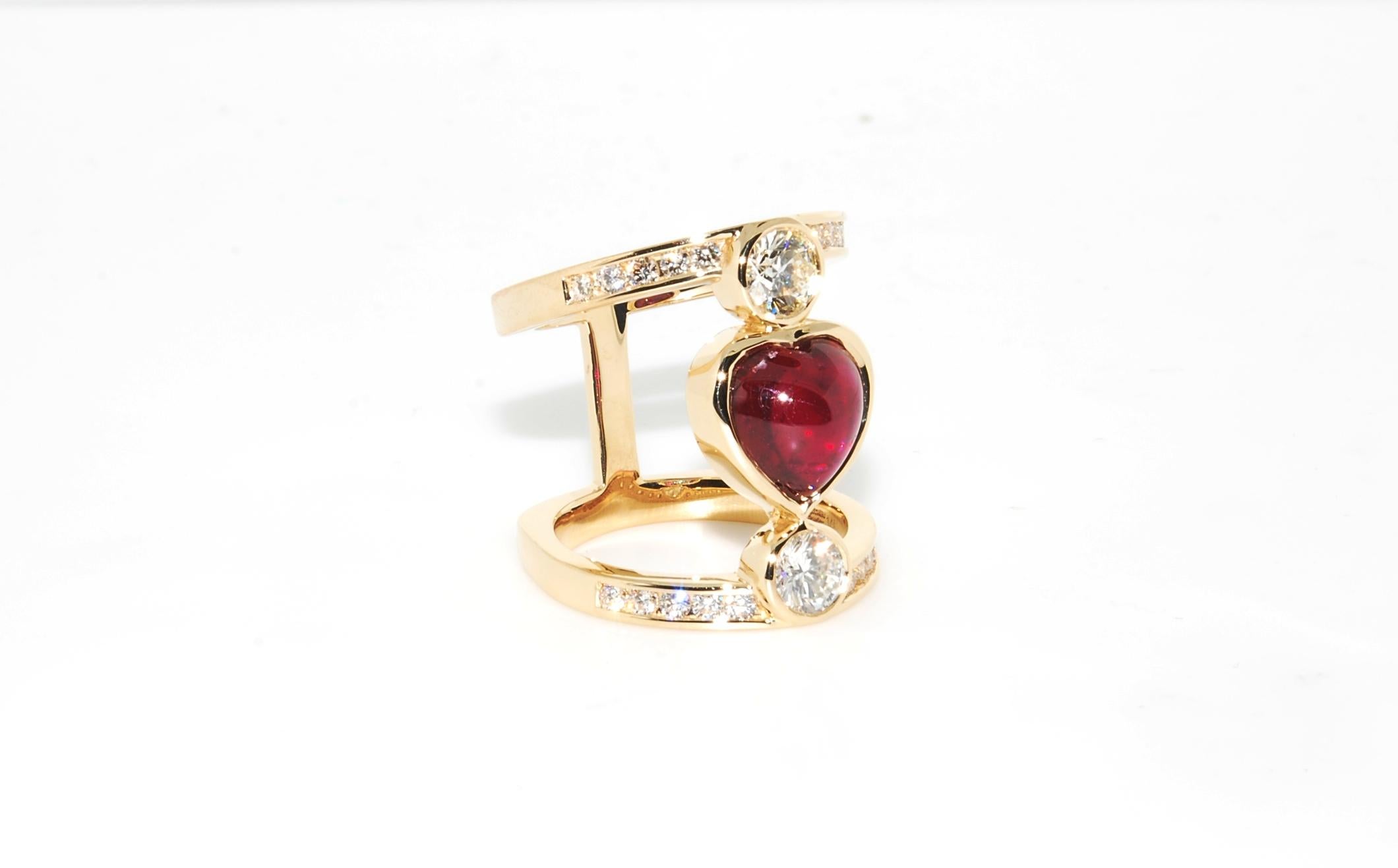 One of one design by Erica Sanchez-Hawkins. Unique Heart Shape Ruby Cabochon flanked vertically by two Ideal cut half carat diamonds, H/I color and VS2 and SI1 clarity. The ring has a split-shank and also has a euro shank back to prevent spin. The