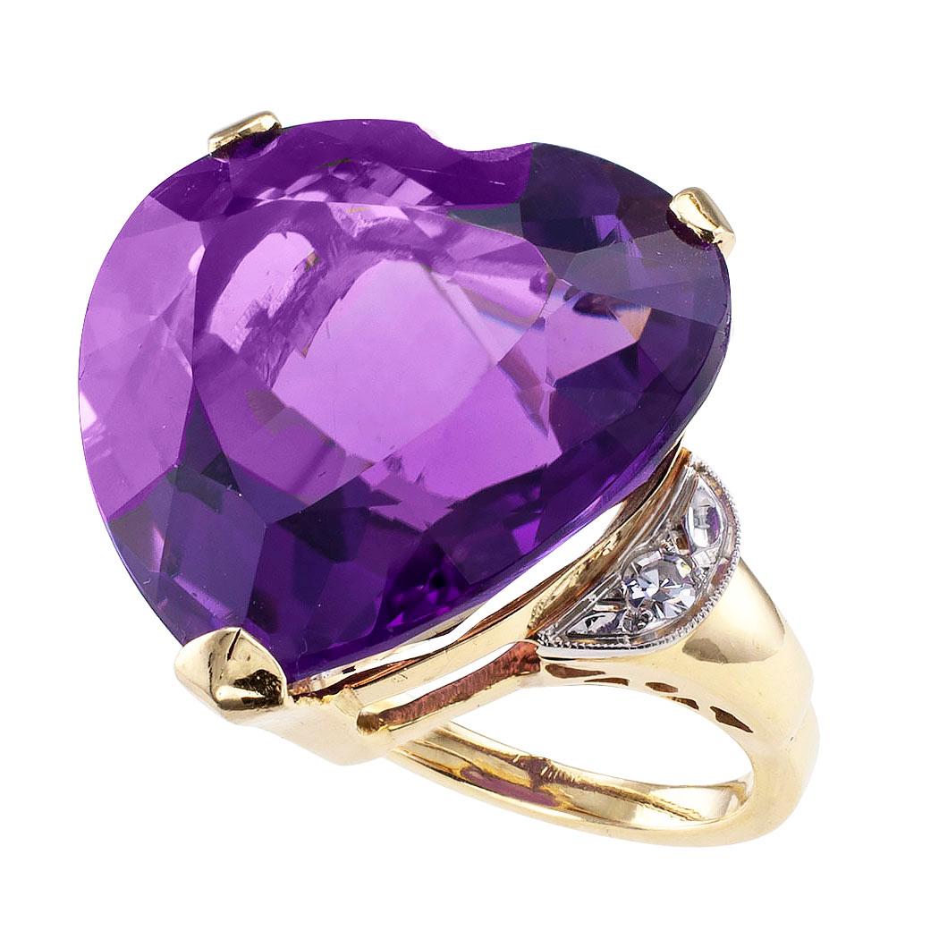 Heart shaped amethyst diamond and gold cocktail ring circa 1960. Showcasing a heart-shaped amethyst weighing approximately 23.00 carats, between halfmoon-shaped shoulders set with a pair of single-cut diamonds totaling approximately 0.06 carat,