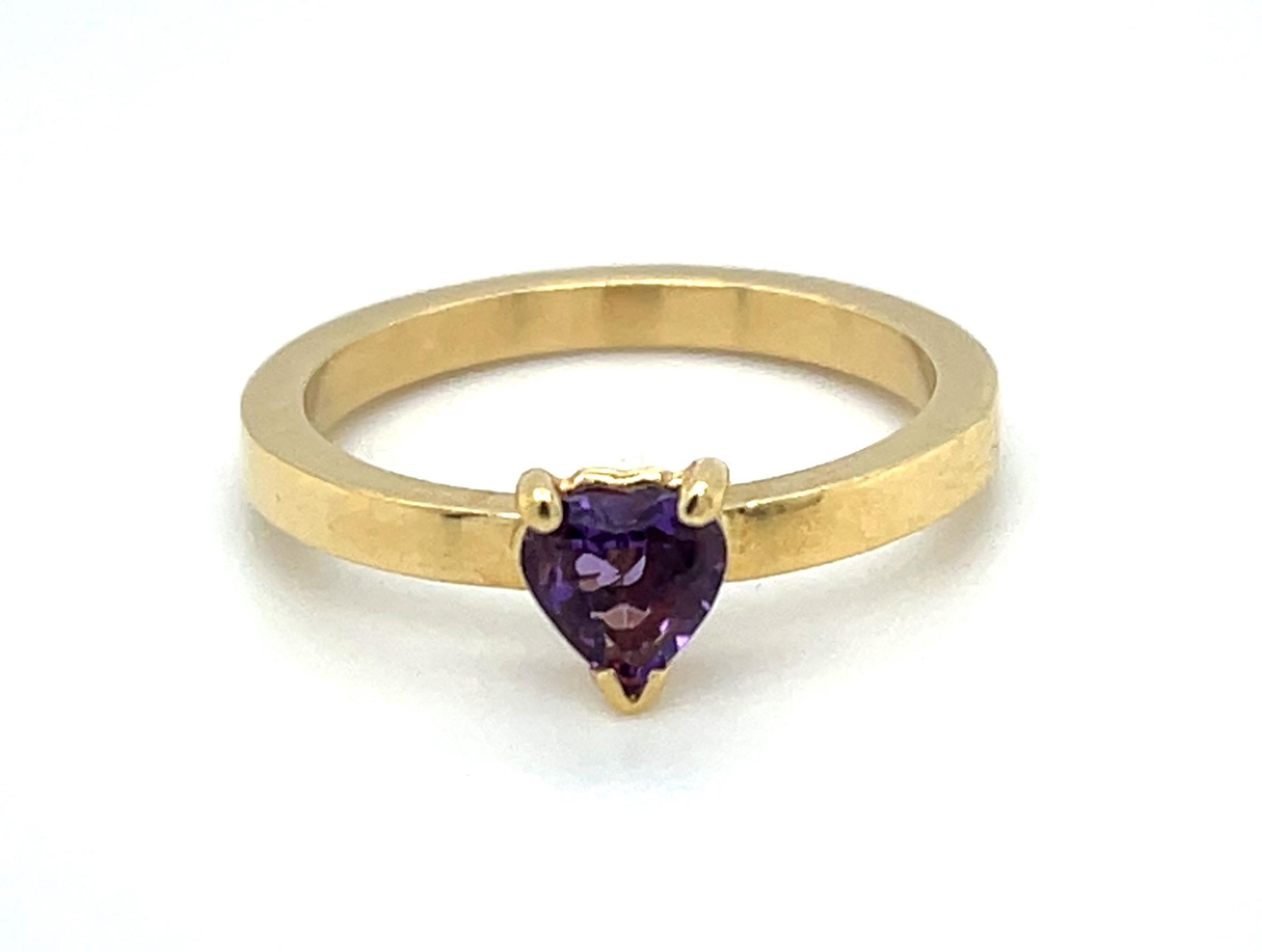 A pretty little heart-shaped amethyst is featured in this stylish 18k yellow gold ring. The band is wide with polished flat sides, designed to be either worn alone or easily 