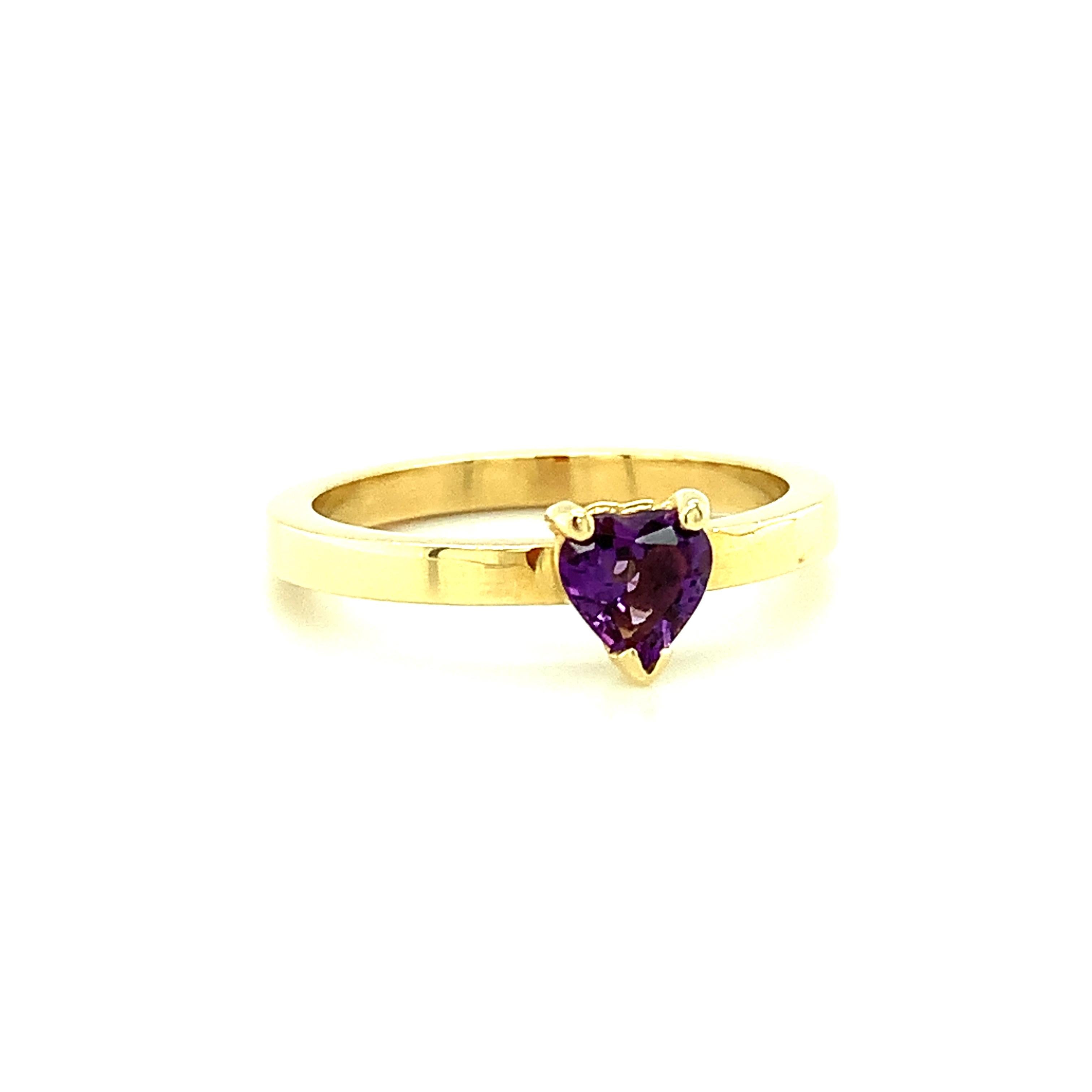 A pretty little heart-shaped amethyst is featured in this stylish 18k yellow gold ring. The band is wide with polished flat sides, designed to be either worn alone or easily 