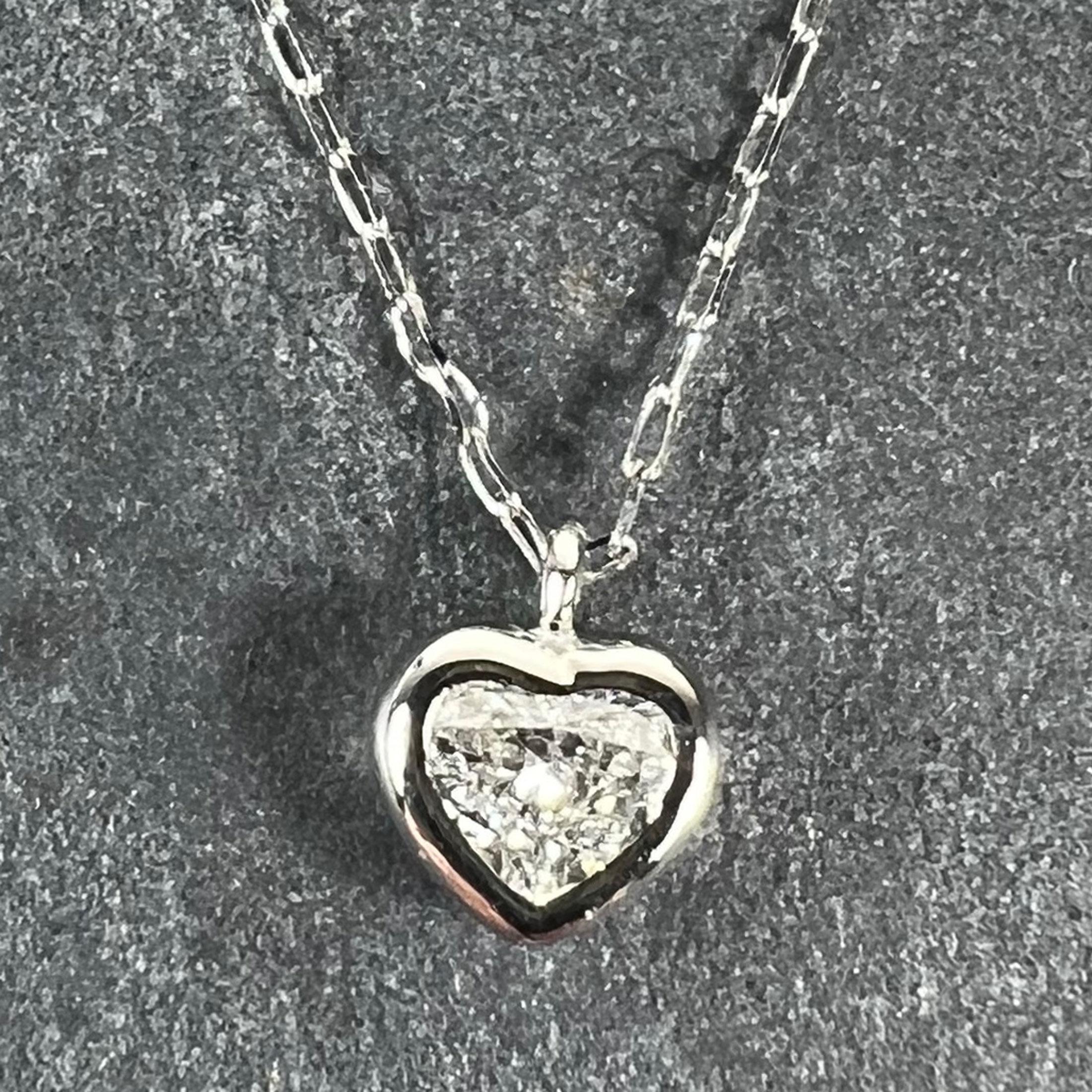 Un ciondolo in platino con un diamante a forma di cuore di 3 x 3,5 x 1,5 mm per un peso di 0,14 carati. La purezza stimata è SI, il colore G-H (la pietra è stata valutata nella montatura, quindi sono stati applicati i gradi del gruppo). Il diamante