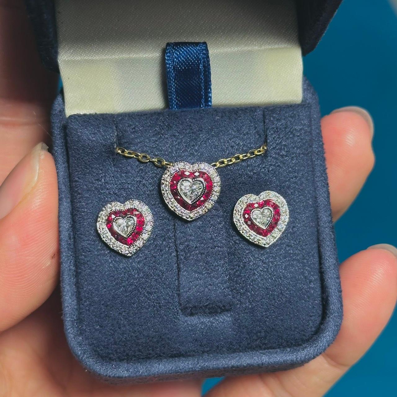 Crafted in 14k white gold, these lovely heart shaped stud earrings and pendant jewelry set  offer a beautiful combination of sophistication and charm. The center heart shaped diamonds grade G color, VS clarity. A frame of French cut rubies, and
