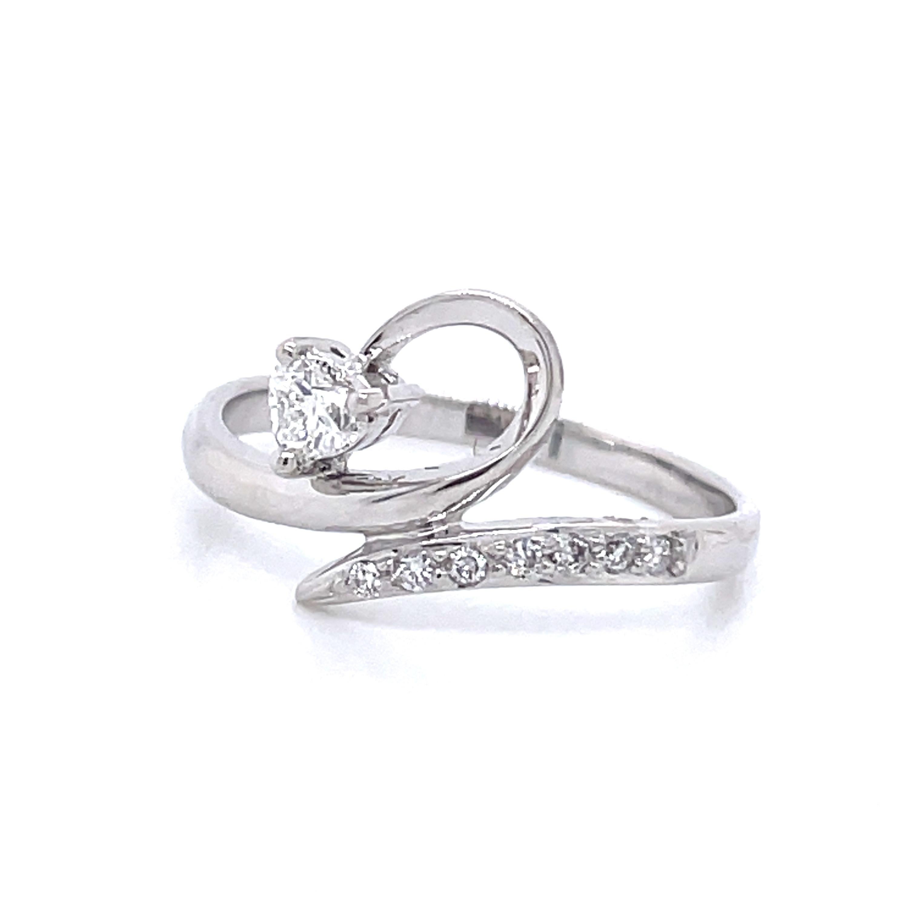 ts distinctive design—a half heart swirl leading to a heart-shaped diamond, totaling 0.13 carats, delicately placed at the end. 

Seven round diamonds, totaling 0.05 carats, elegantly grace the shoulders, enhancing the ring's allure.

This unique