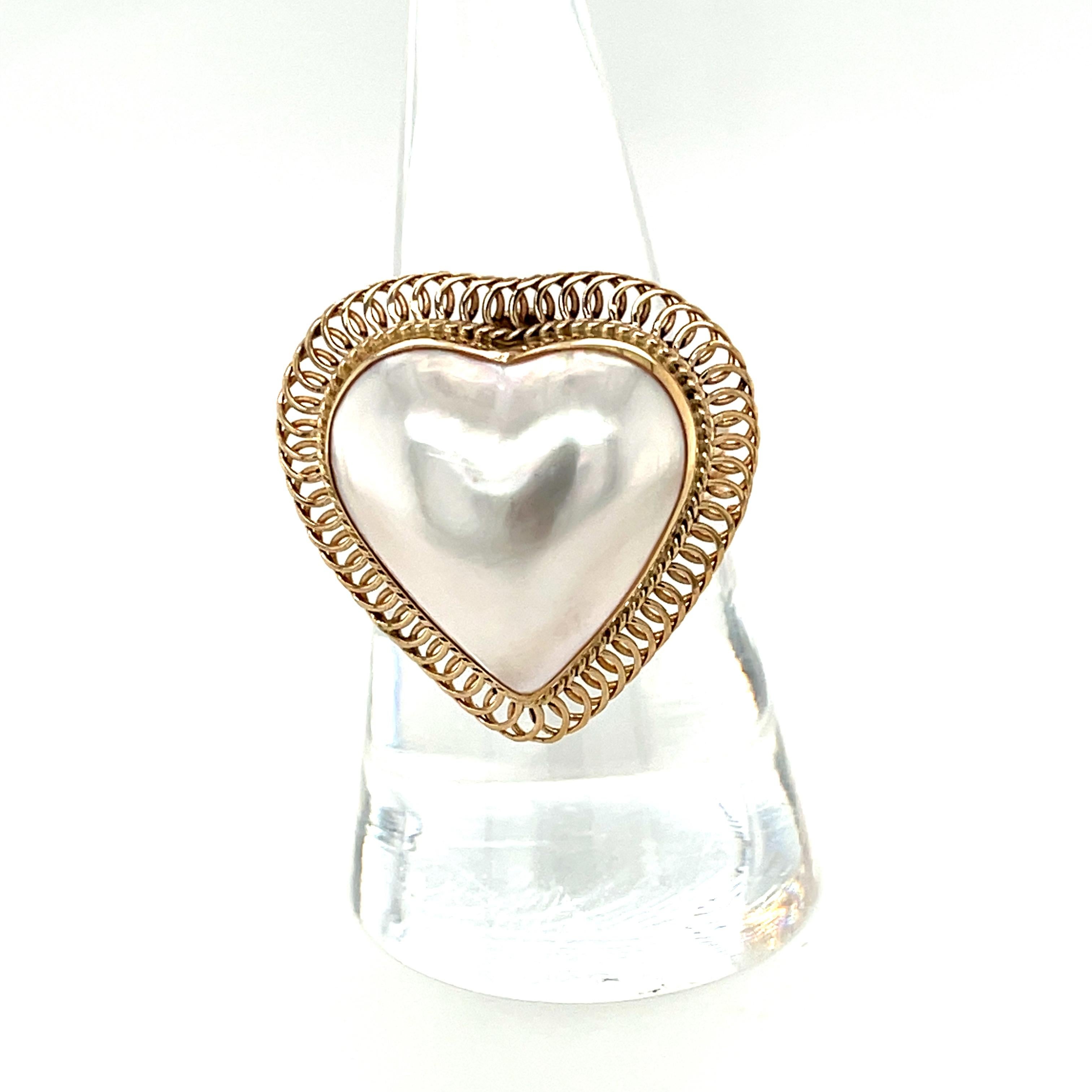 This exquisite handmade ring features a large, heart-shaped Mabe pearl that has been framed with an intricate spiral design crafted from delicate 14k yellow gold wire. The 18mm pearl has beautiful luster and pearlescence and it certainly has a