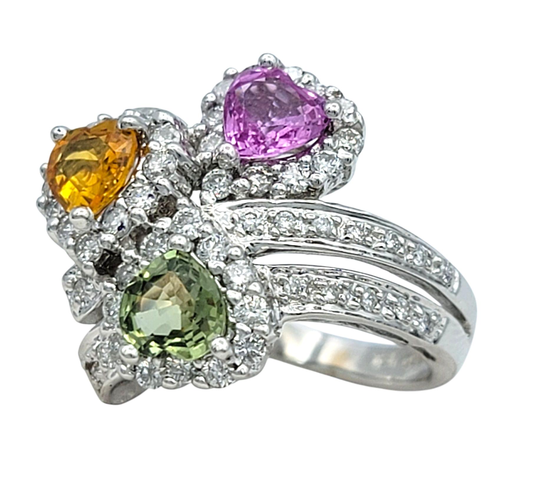 Ring Size: 5.75

This colorful and intricately designed ring showcases a trio of heart-shaped sapphires in playful hues of pink, green, and orange. The saturated colors of the sapphires bring a lively, vibrant feel to the ring, enhanced by their