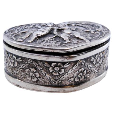 Heart-shaped silver pill box with embossed angel decoration on the hinged lid