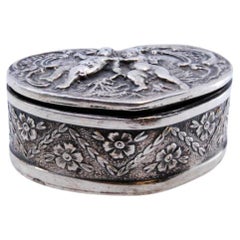 Heart-shaped silver pill box with embossed angel decoration on the hinged lid