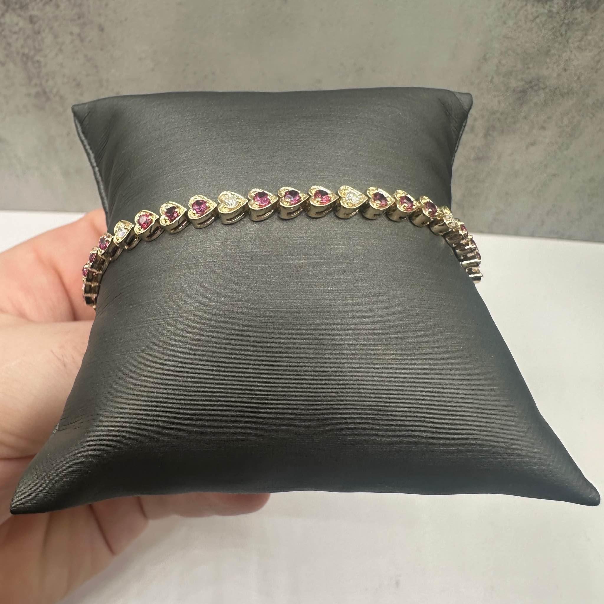 This exquisite Luscious Heart Shaped Tennis Bracelet in 14kt yellow gold features approximately 2ctw of vibrant round rubies, beautifully complemented by 0.45ctw of natural GH VS round diamonds, creating a stunning contrast of color and sparkle.