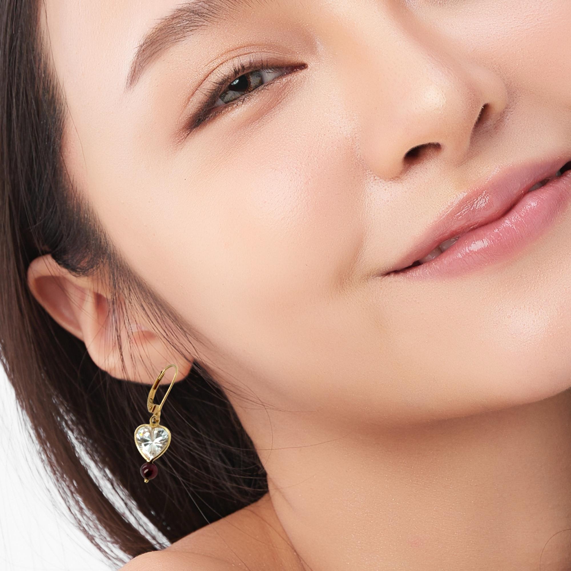 Delicado destello con un toque romántico.
Estos encantadores pendientes colgantes tienen piedras de topacio blanco en forma de corazón (8x8 mm) suspendidas de aros de palanca de oro amarillo macizo de 14k. Una sola cuenta de turmalina cuelga