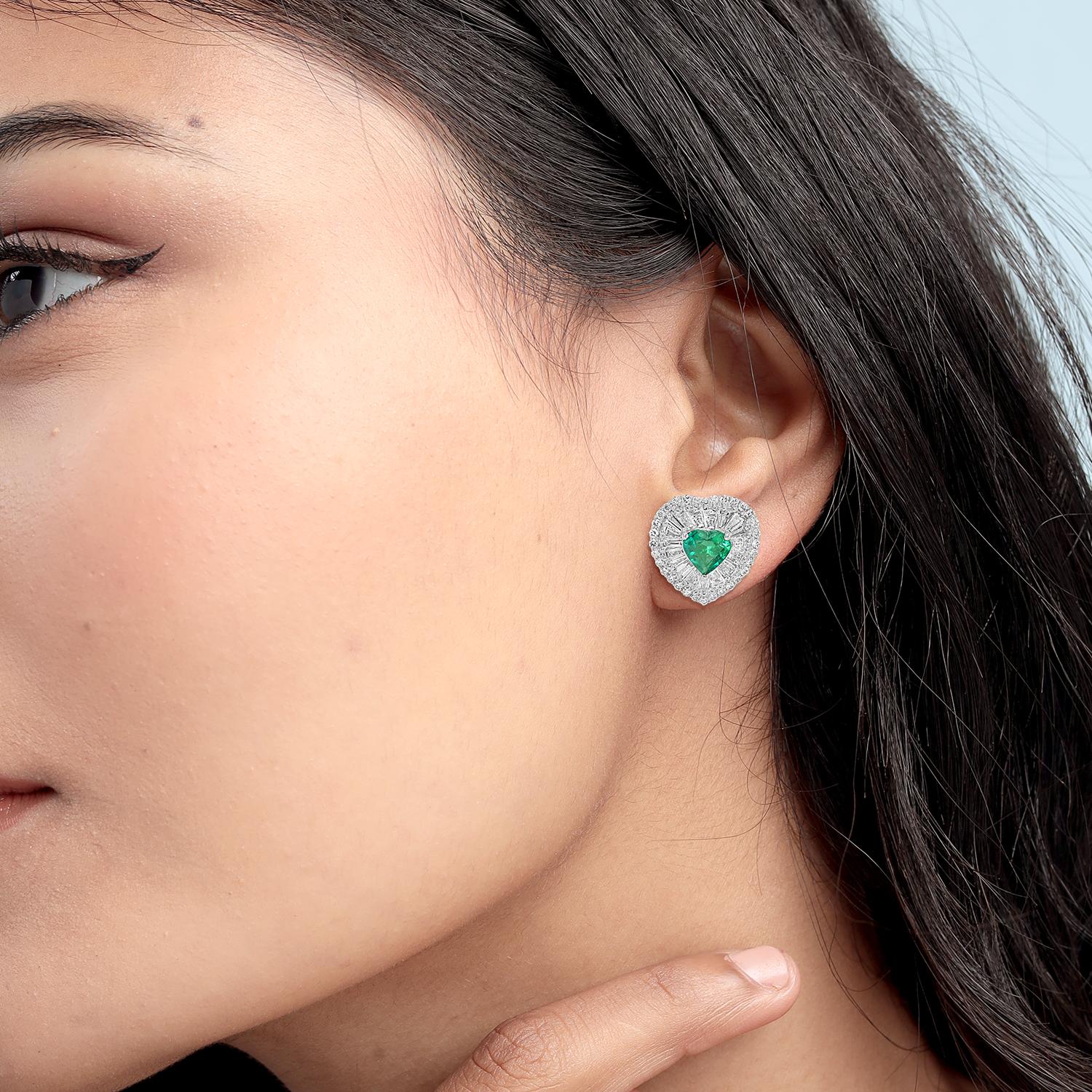 Conçus dans une douce silhouette en forme de cœur, ces clous d'oreilles en émeraude de Zambie allient couleurs vives et étincelles délicates. Serties en or 18 carats et entourées de plus d'un carat de diamants étincelants, elles offrent un look