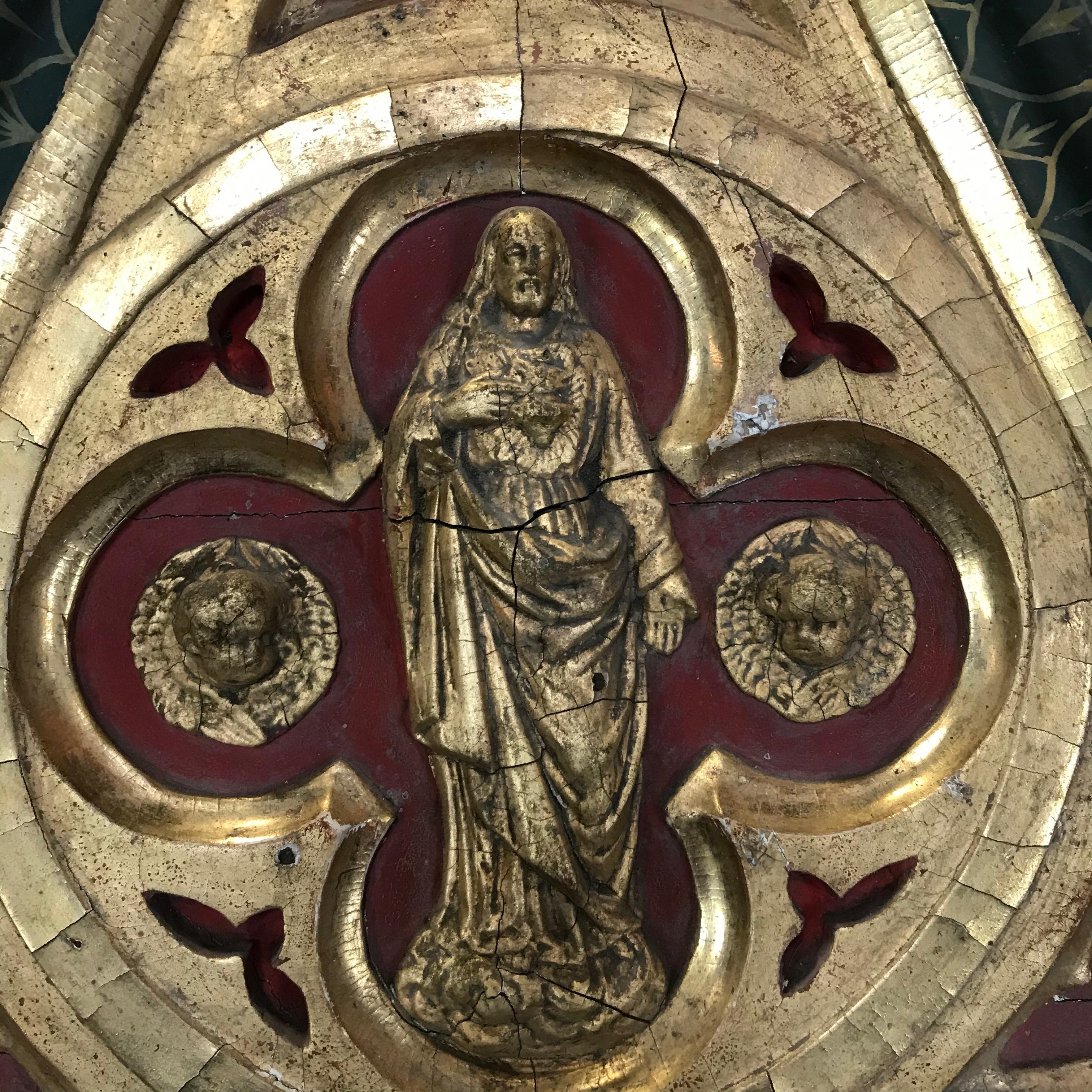 An incredible eye catching piece of wall art mined from a 19th century French church. The wall sculpture is a Gothic shape having carved giltwood and beautifully painted bas relief art at the top of a saint with cherubs. “Confrerie des Dames de
