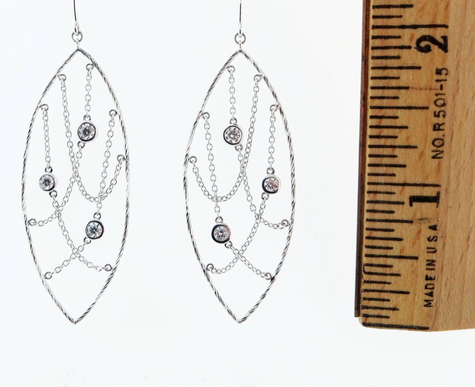 Sensational 18kt. white gold earrings with lots of movement , each earring measures 2 1/4 inches in length, the center of the marquise frame is suspended with three bezel set Hearts on Fire diamonds, lots of dangle and  jiggle ! Easy and fun to