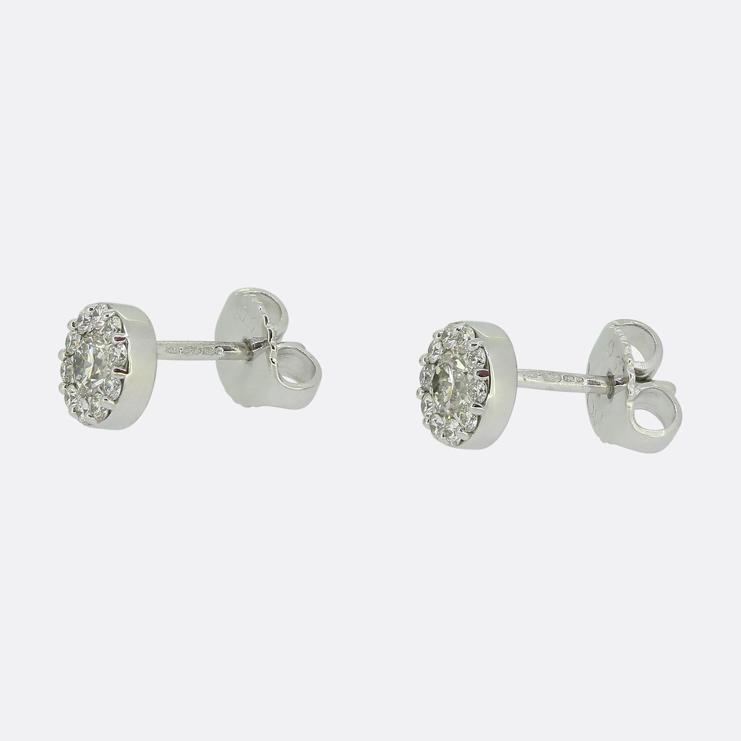 Ecco un bel paio di orecchini a perno di Hearts On Fire. Realizzati in oro bianco 18ct, questi orecchini hanno un design circolare. Al centro, un singolo diamante rotondo bianco dal taglio brillante è circondato da un'aureola di diamanti più piccoli