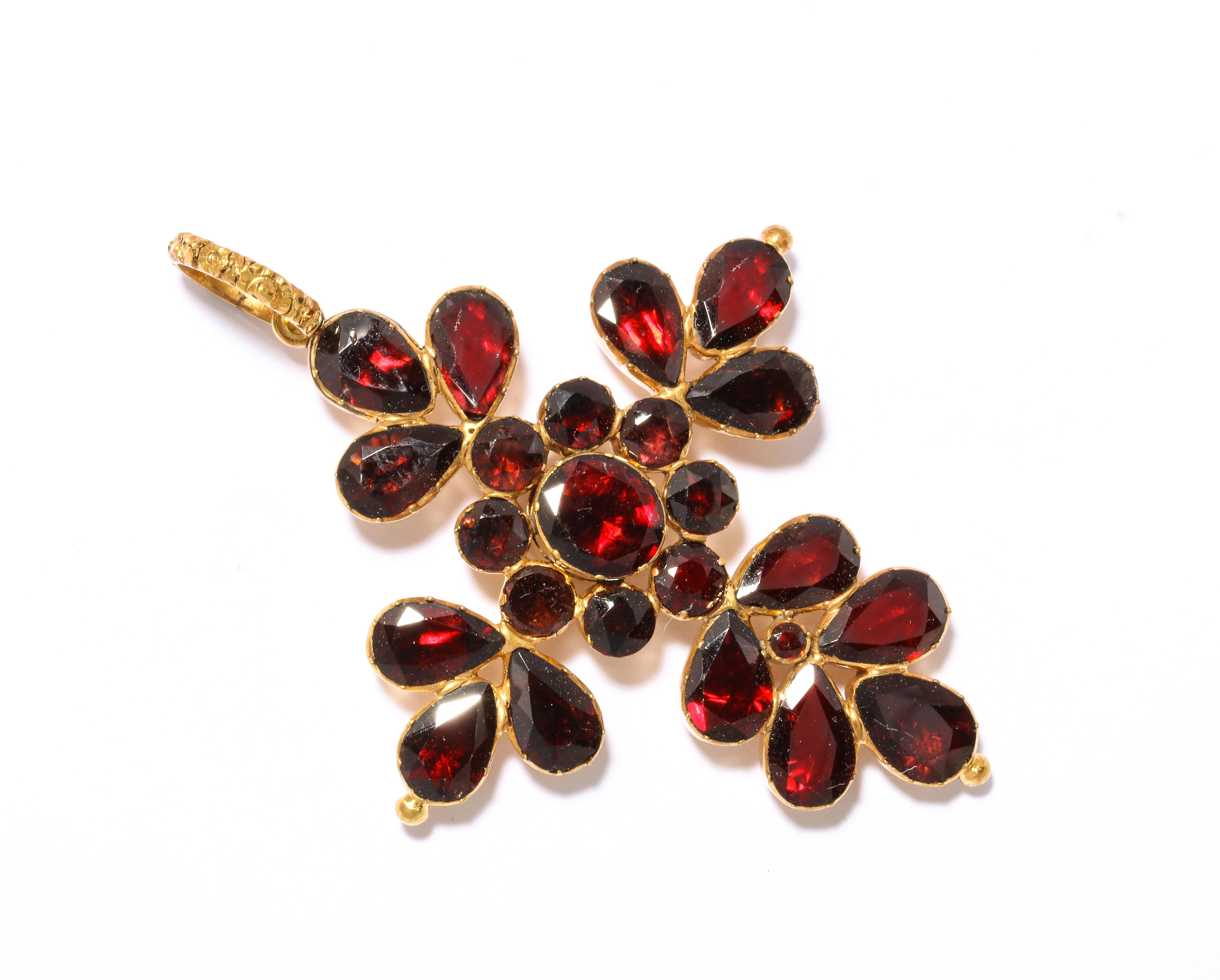 Georgian garnets are magnificent and these are true to the word gleaming in a pendant formed as a floral cross. A central flower is the focus while the oval garnets surrounding are petals. The back is typical Georgian beauty, round pillow backs that