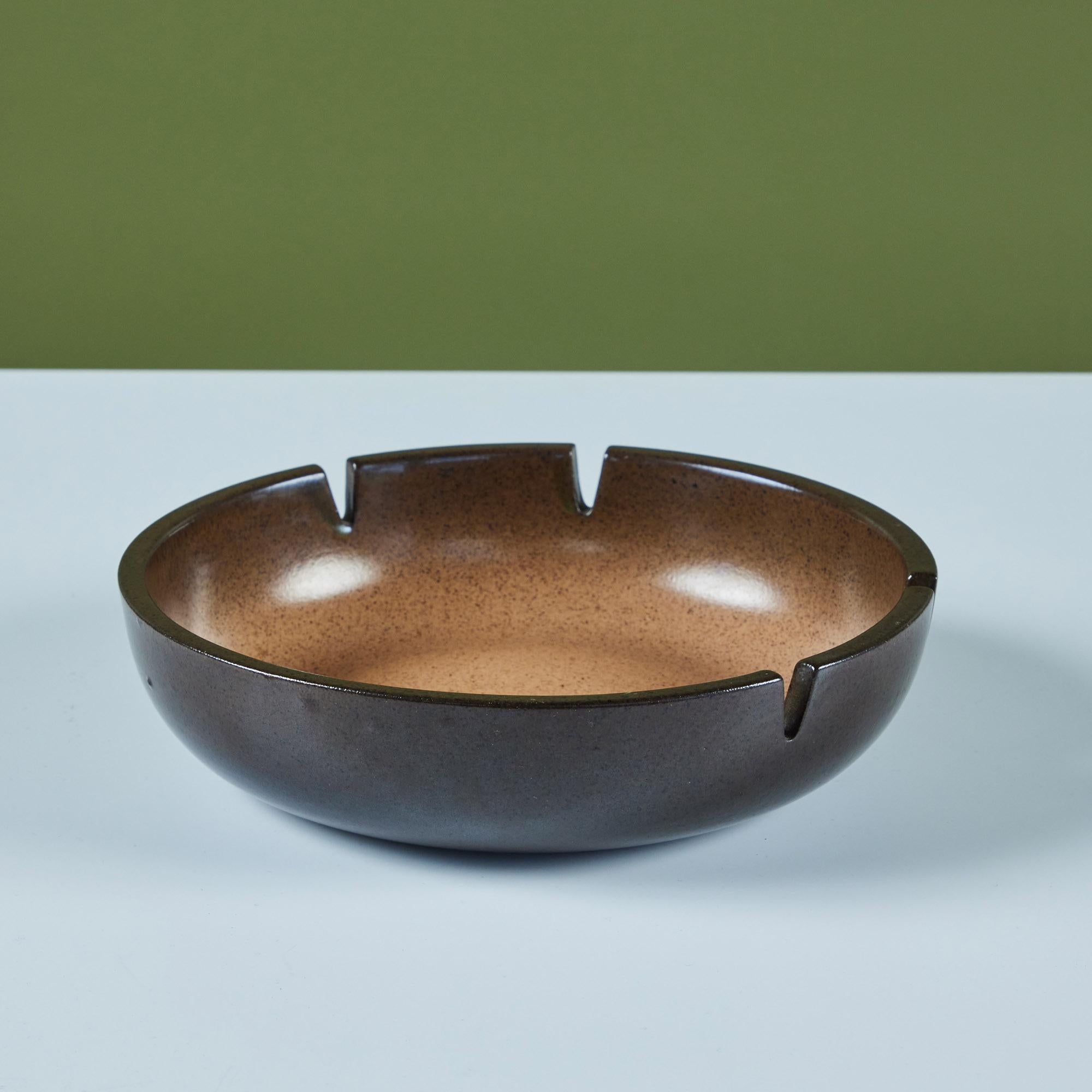 Glazed ceramic ashtray by Heath Ceramics, c.1960s, USA. The ashtray features a dark brown exterior speckle glaze which ombres into a tan speckle glaze on the interior. There are four holding slots for cigarettes. Can also be used as a decorative