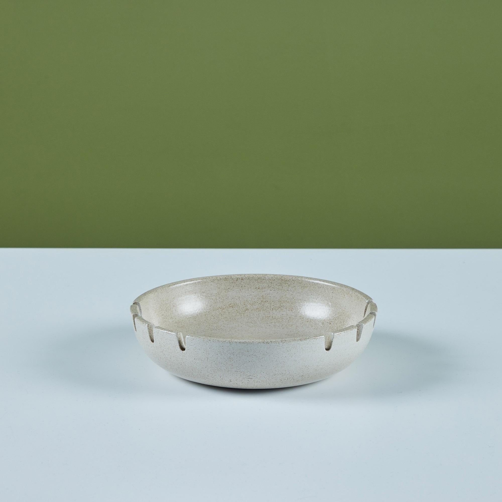 Glazed ceramic ashtray by Heath Ceramics, c.1960s, USA. The ashtray features an all over cream speckle glaze. There are eight holding slots for cigarettes. Can also be used as a decorative catchall or soap dish.
Inscribed on the underside, “Heath -