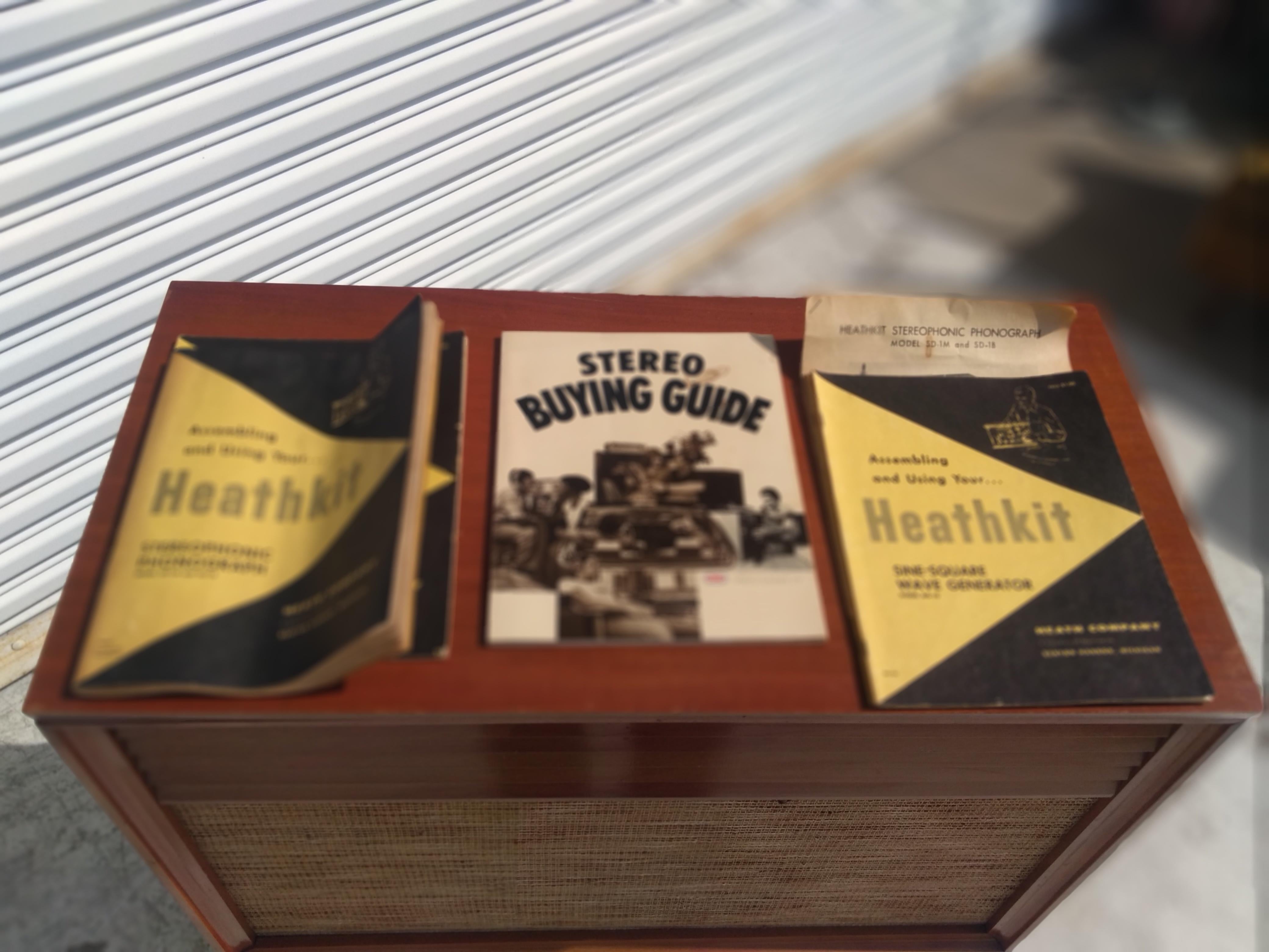 These Heathkit stereos were handmade by the buyer as a project. They're very collectible and sought out. This is a SD-1 model. The cabinet is made of mahogany and it sits on brass extended legs. The top opens up to reveal the stereo amp and the