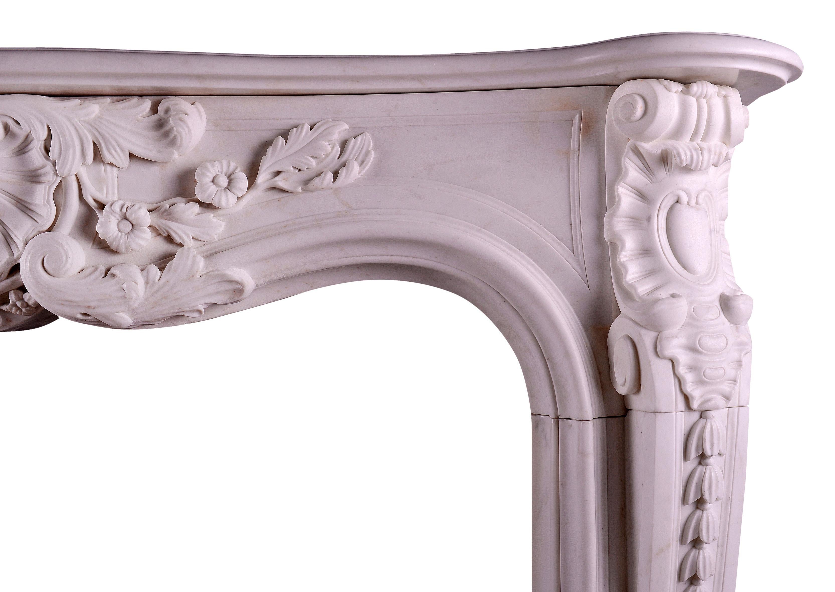 A heavily carved 19th century statuary white marble fireplace in the Louis XV manner. The jambs with stiff acanthus leave to the base, surmounted by bell flowers and scrollwork. The frieze with a carved shell to centre flanked by scrollwork and leaf