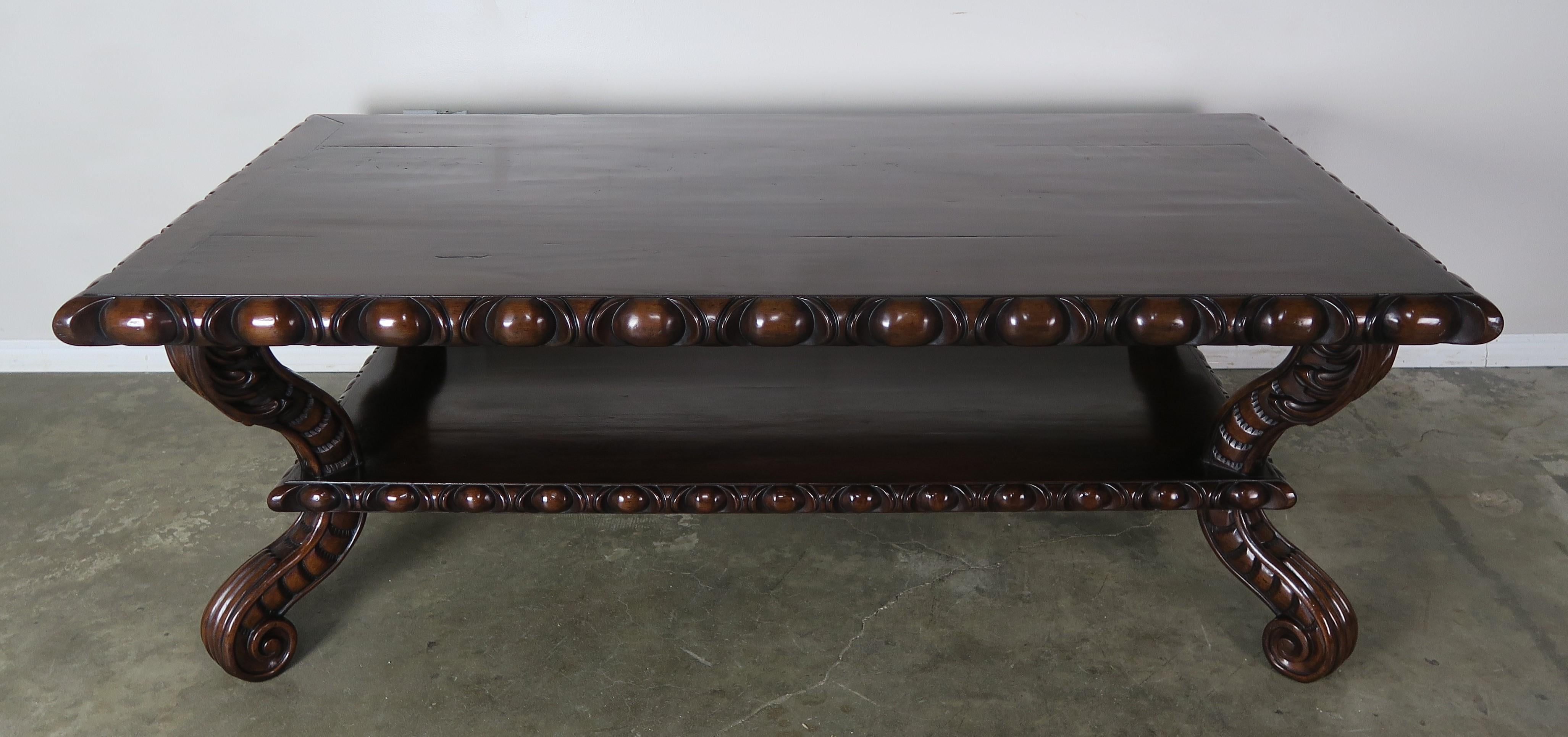 Large heavy carved Spanish style walnut coffee table with bottom tier suitable for storage. The table is beautifully decorated with egg and dart detailing around the perimeter of the top. The table stands on four scrolled legs that are also heavily