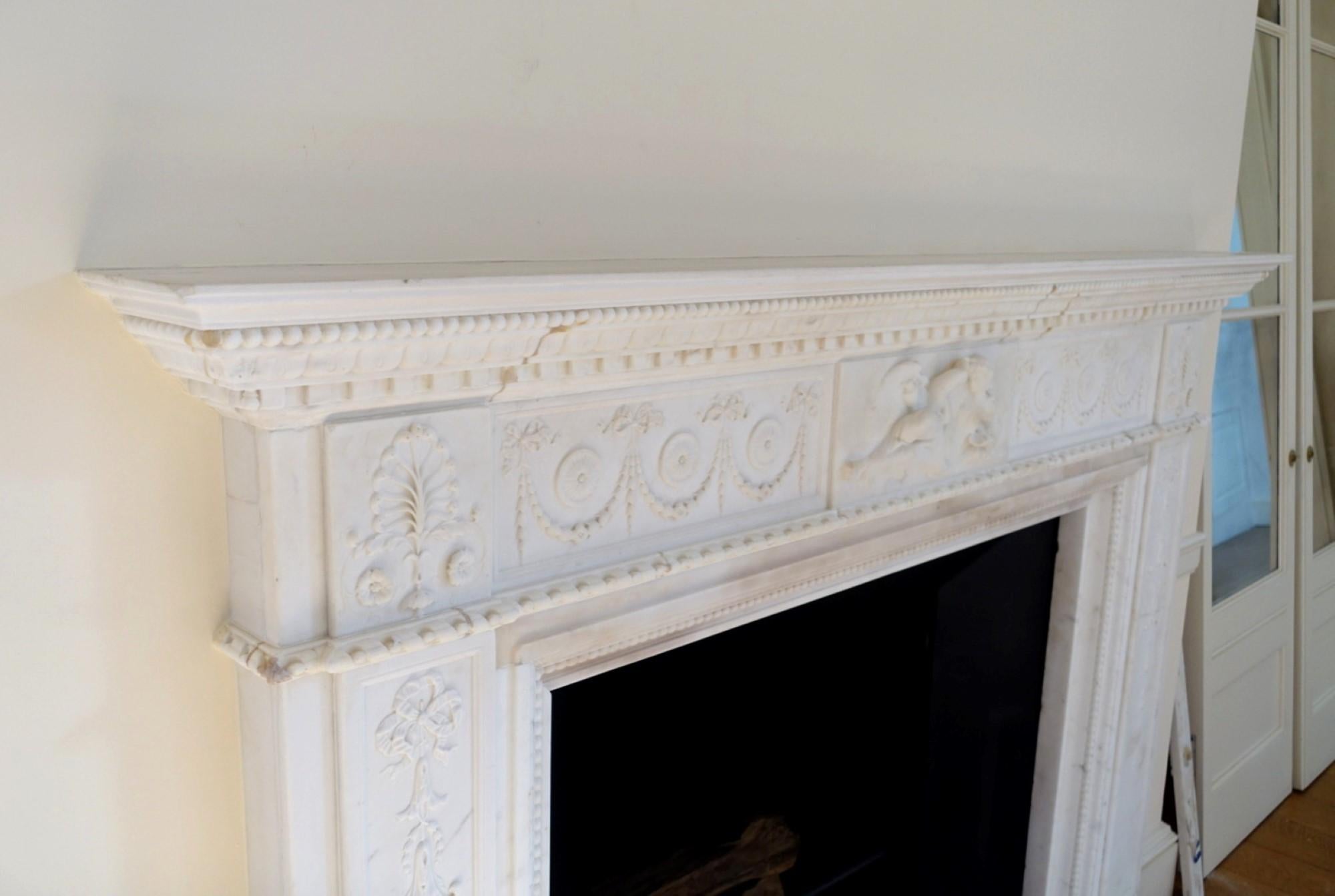 Heavily hand carved 1920's, statuary white marble mantel depicting the Greek mythology story of Leda and Zeus, in the form of a swan. The story is carved in the center of the mantel and has a ribbon & floral design on the sides. Hearth is not