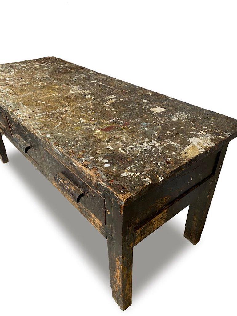 Magnifique établi / table de travail utilitaire belge des années 1950 comprenant 3 tiroirs avec des poignées en bois sculpté. Construit en bois massif avec une belle patine vieillie. L'usure est conforme à l'âge et à l'utilisation. Voir les photos